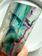 Polished fluorite slab photographed in natural light highlighting teal, green, and magenta crystal bands