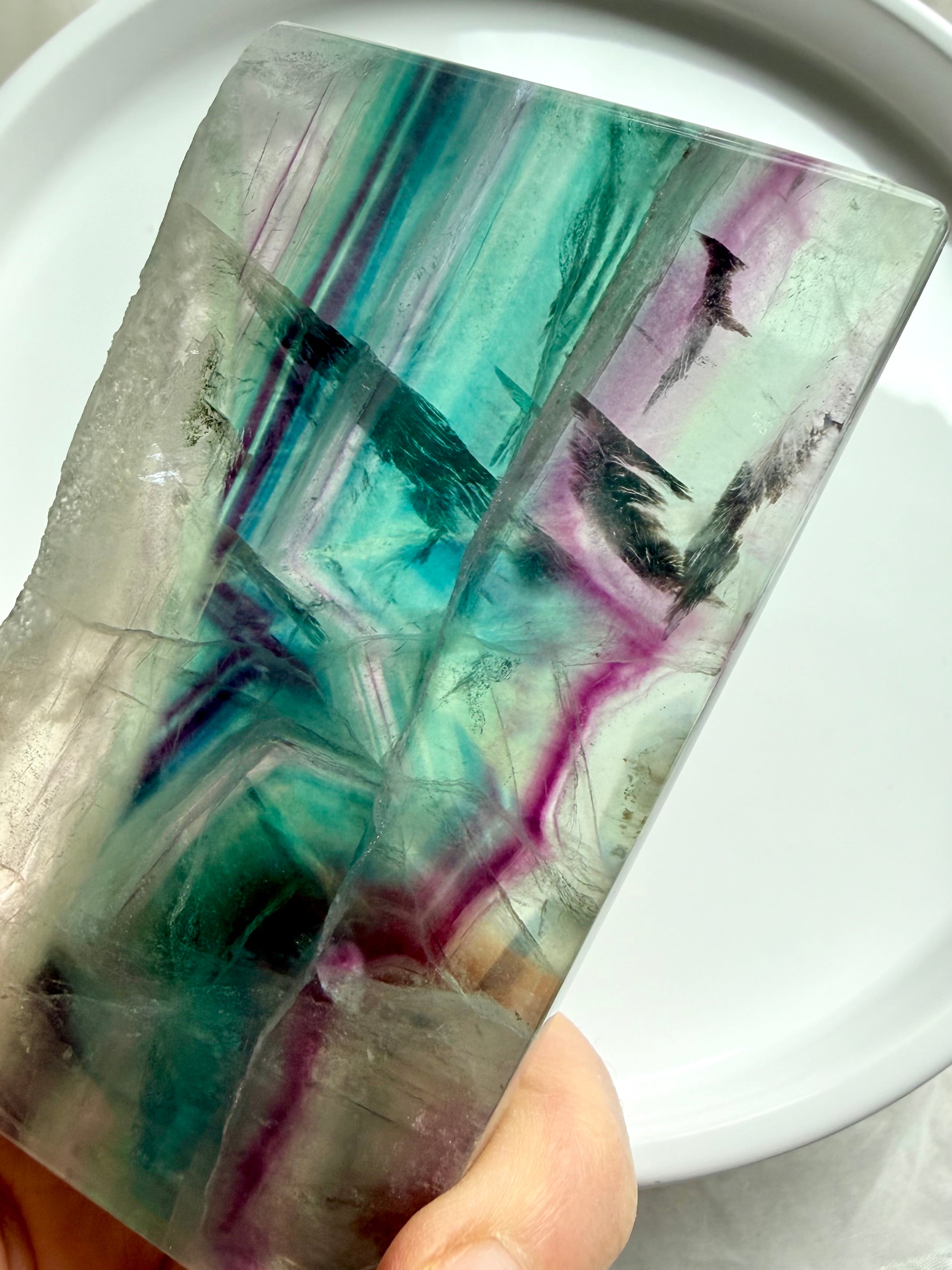 Polished fluorite slab photographed in natural light highlighting teal, green, and magenta crystal bands