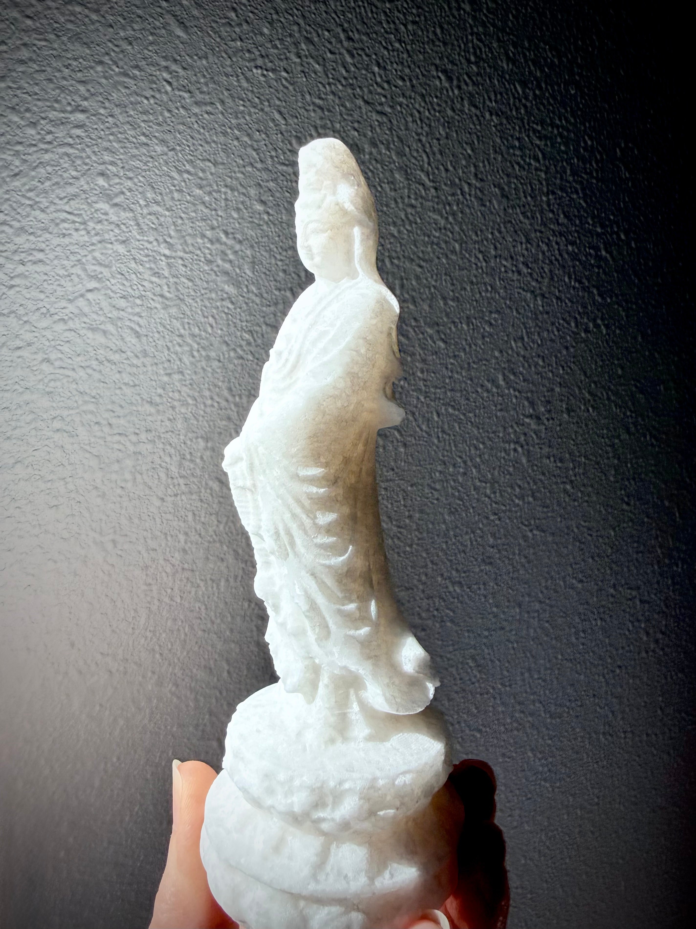 White Jade Quan Yin statue held in hand showing soft translucency and natural crystalline sparkle