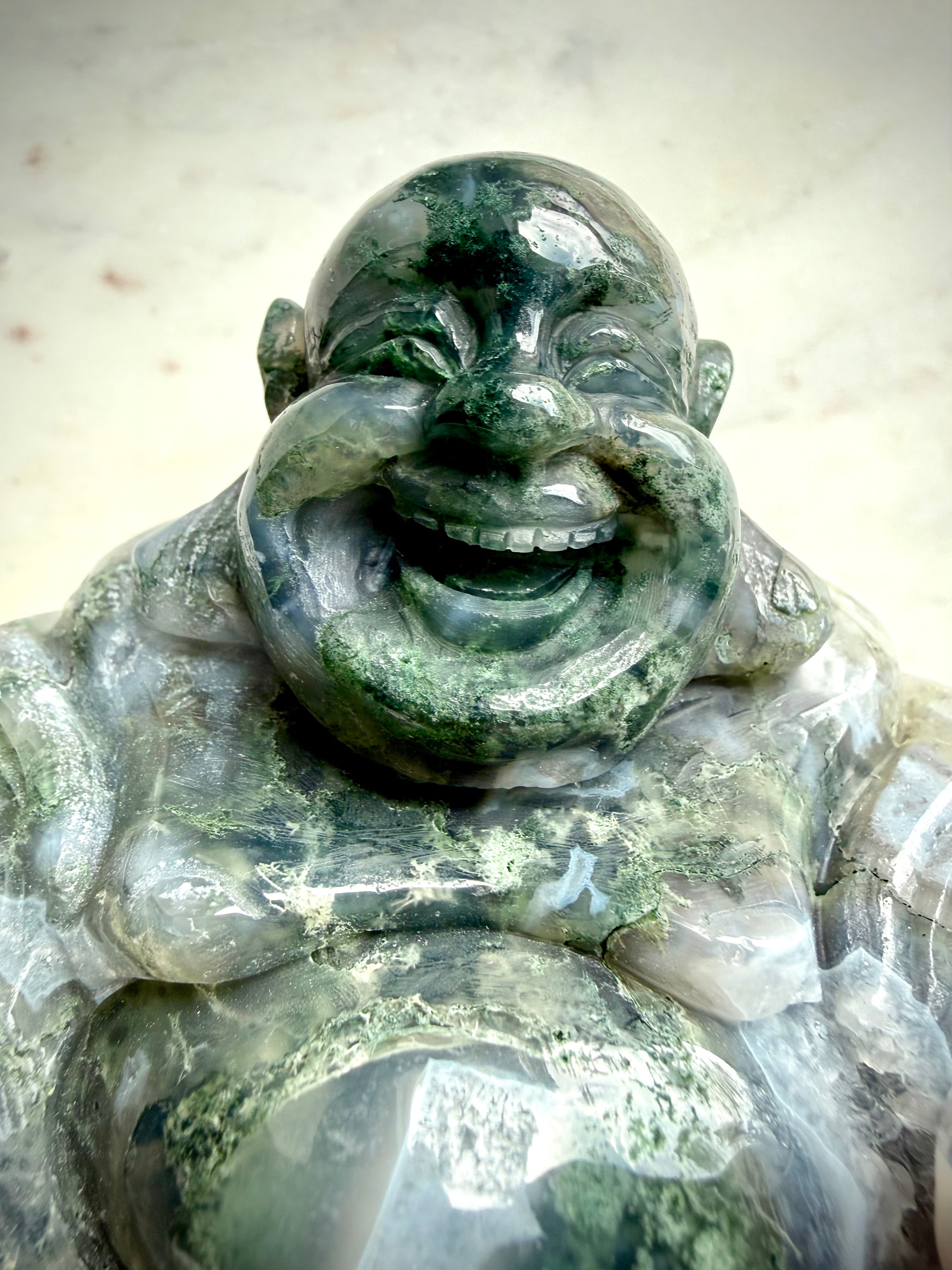 Closeup view of a Large Moss Agate Laughing Buddha statue highlighting detailed hand carving