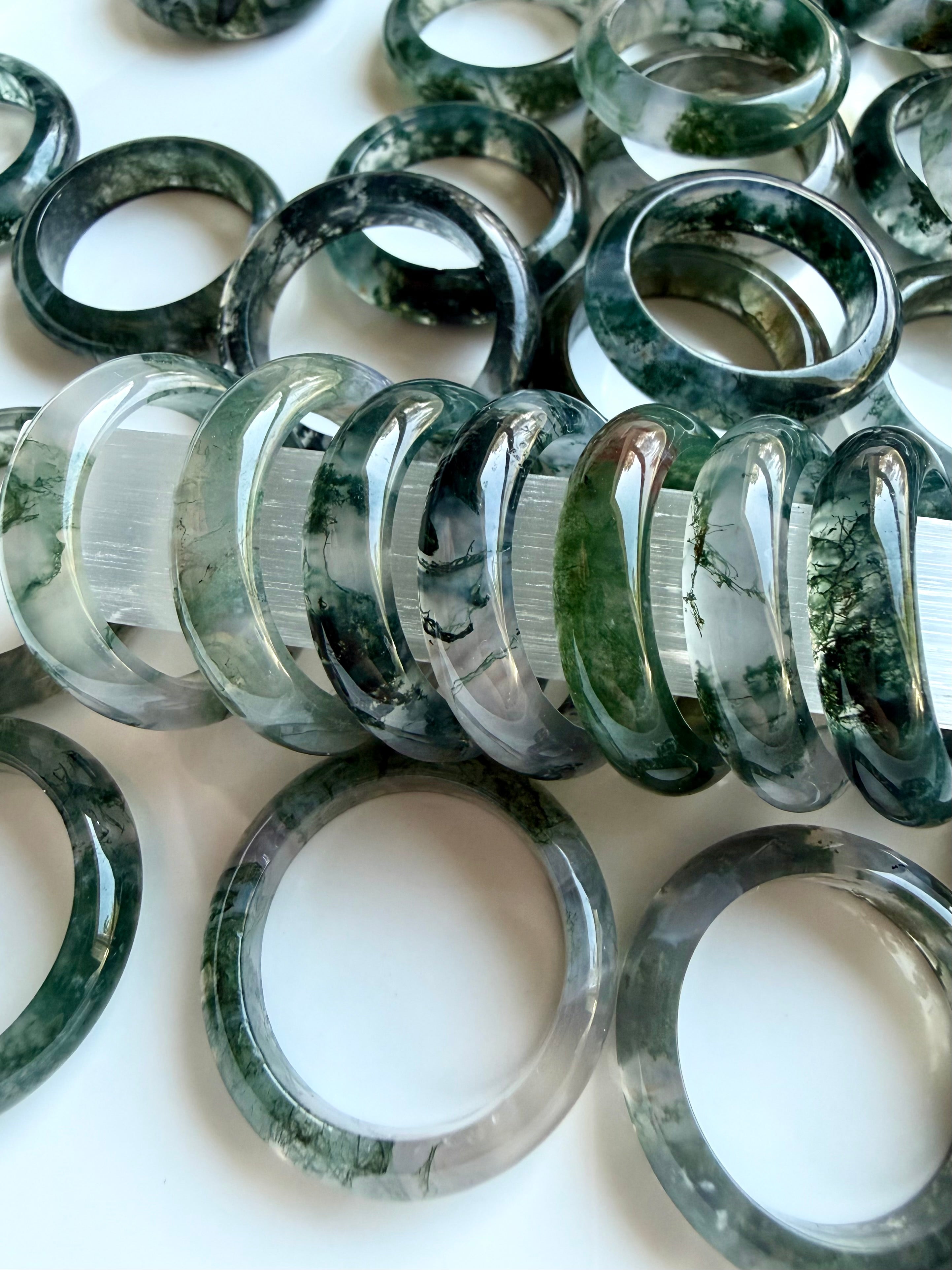 collection of moss agate rings in soft lighting highlighting translucency and inclusions, healing crystal jewelry for calm and grounding