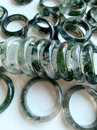 collection of moss agate rings in soft lighting highlighting translucency and inclusions, healing crystal jewelry for calm and grounding