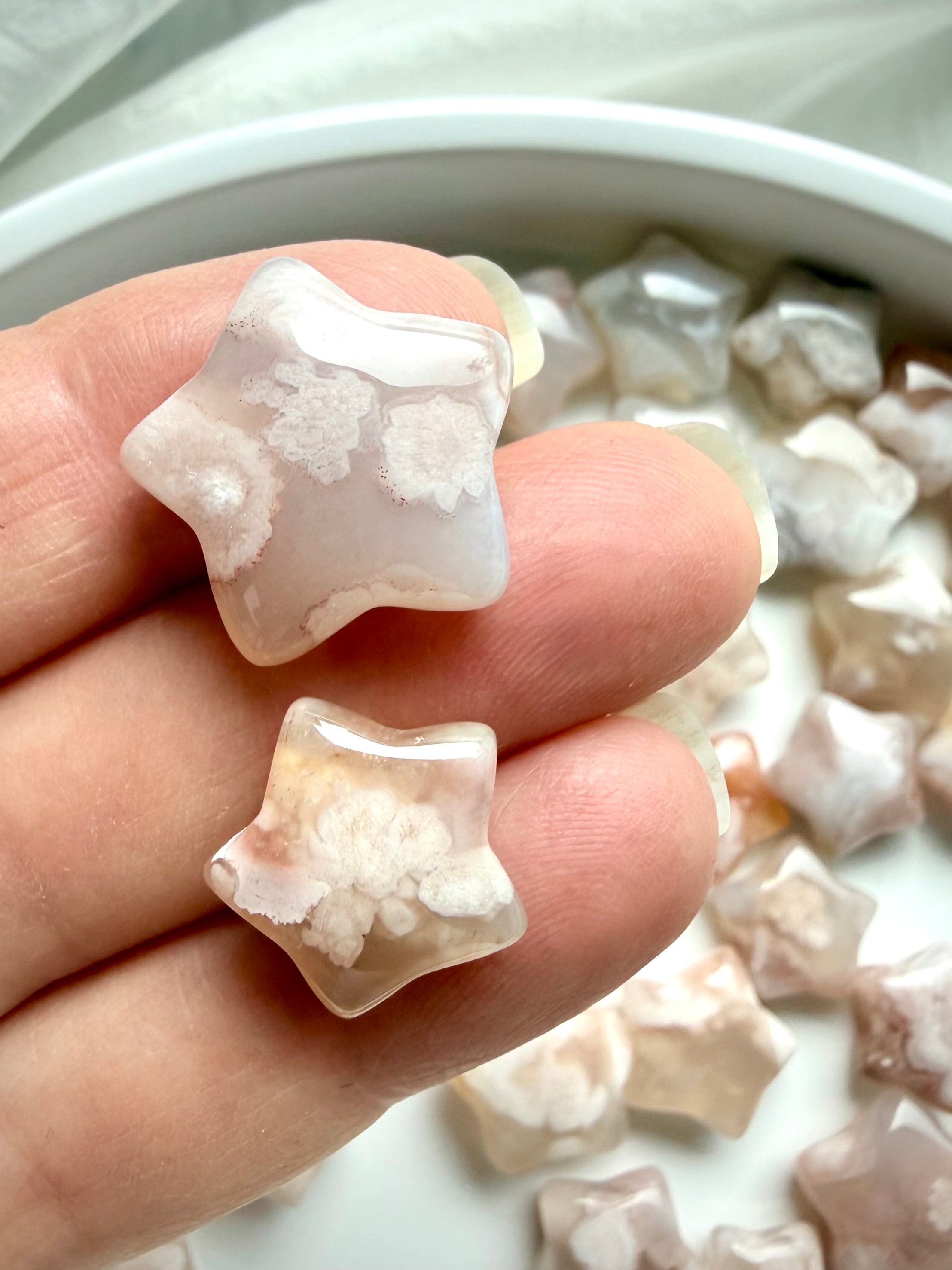 Close up of two mini Flower Agate star carvings with floral patterns and dreamy pastel chalcedony tones