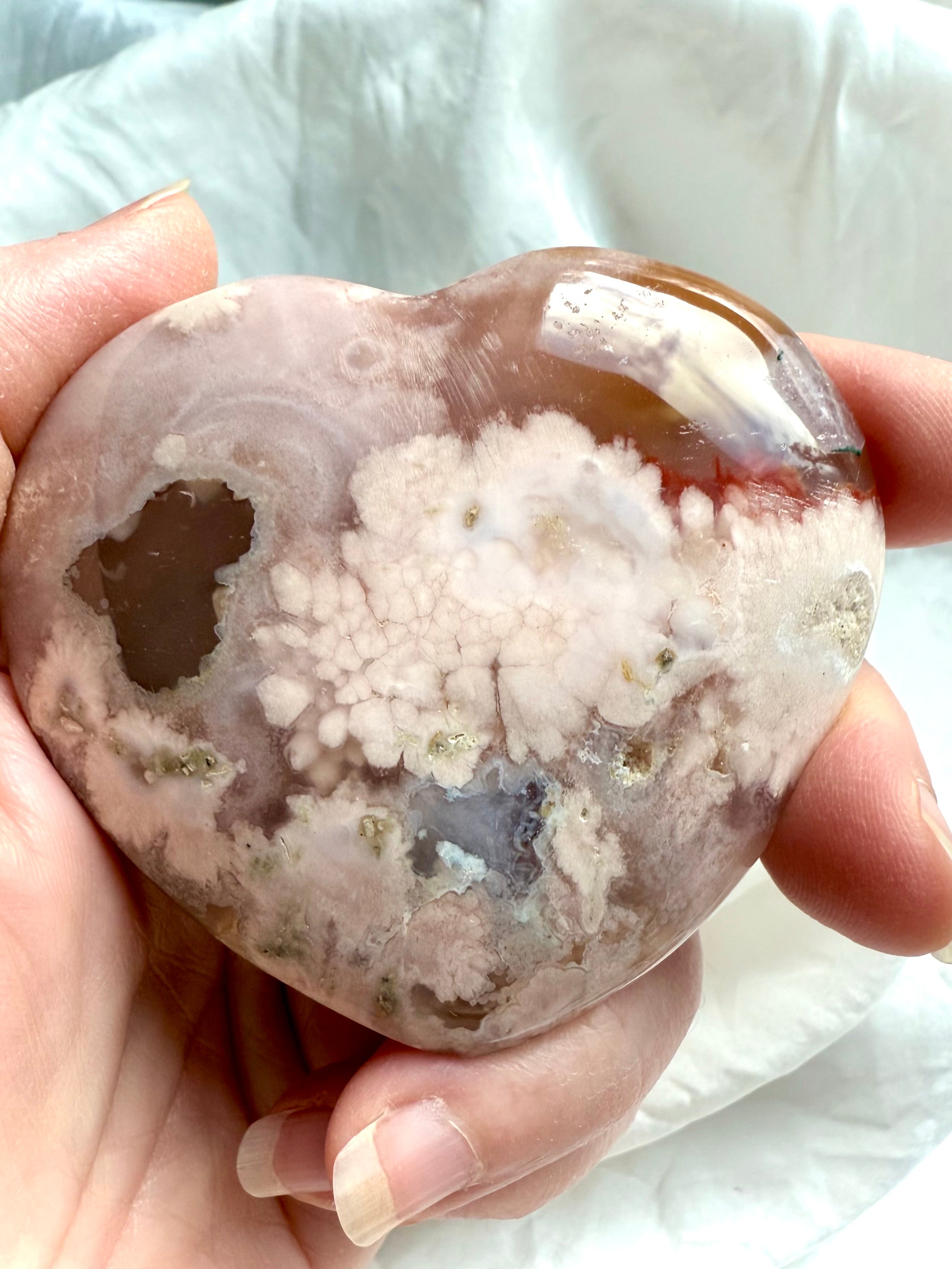 Close-up of polished Flower Agate heart crystal with visible druzy pocket and dreamy pastel patterns
