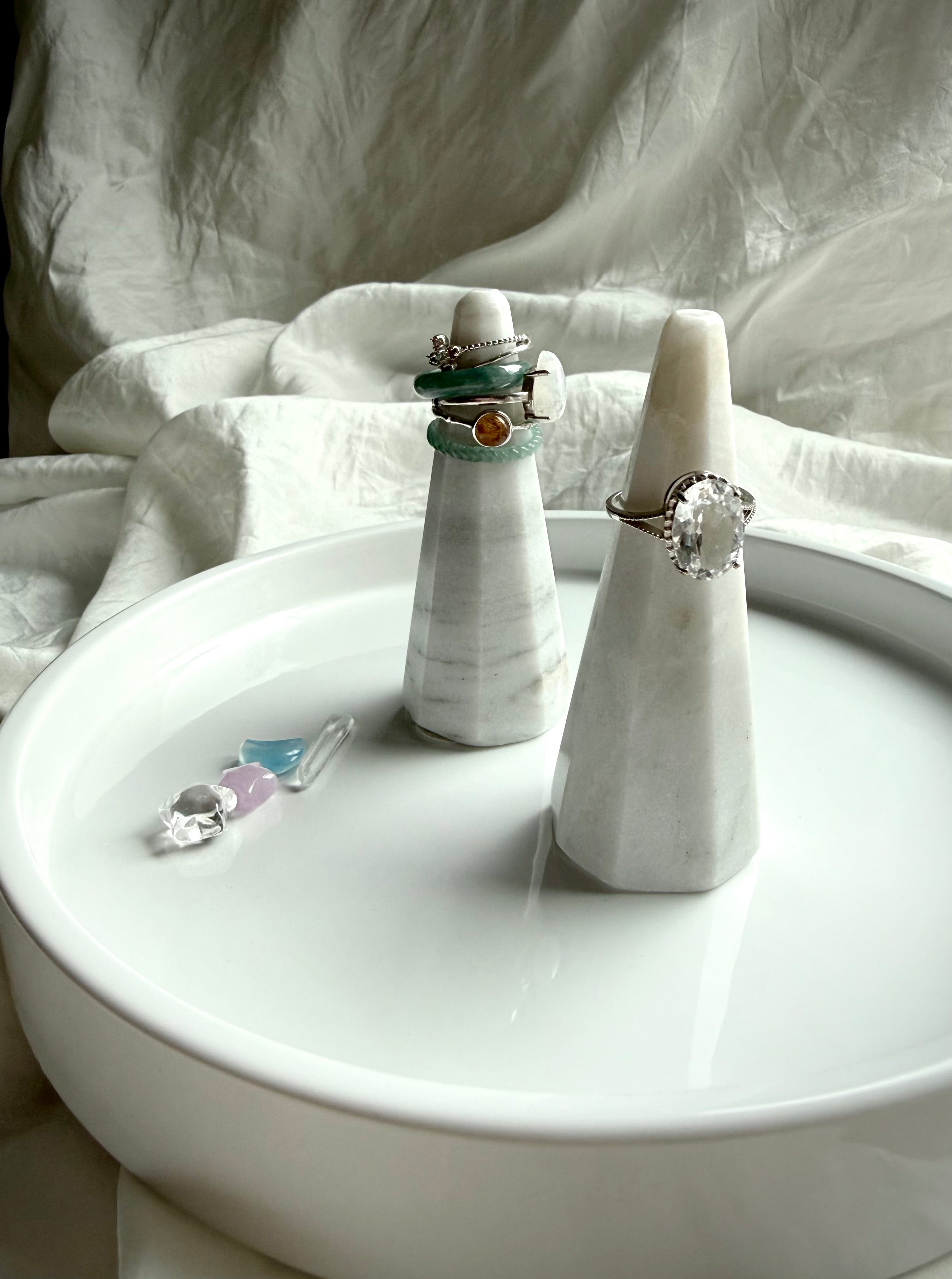 White and gray marble ring holders with faceted sculptural design displayed stacked with rings on vanity tray