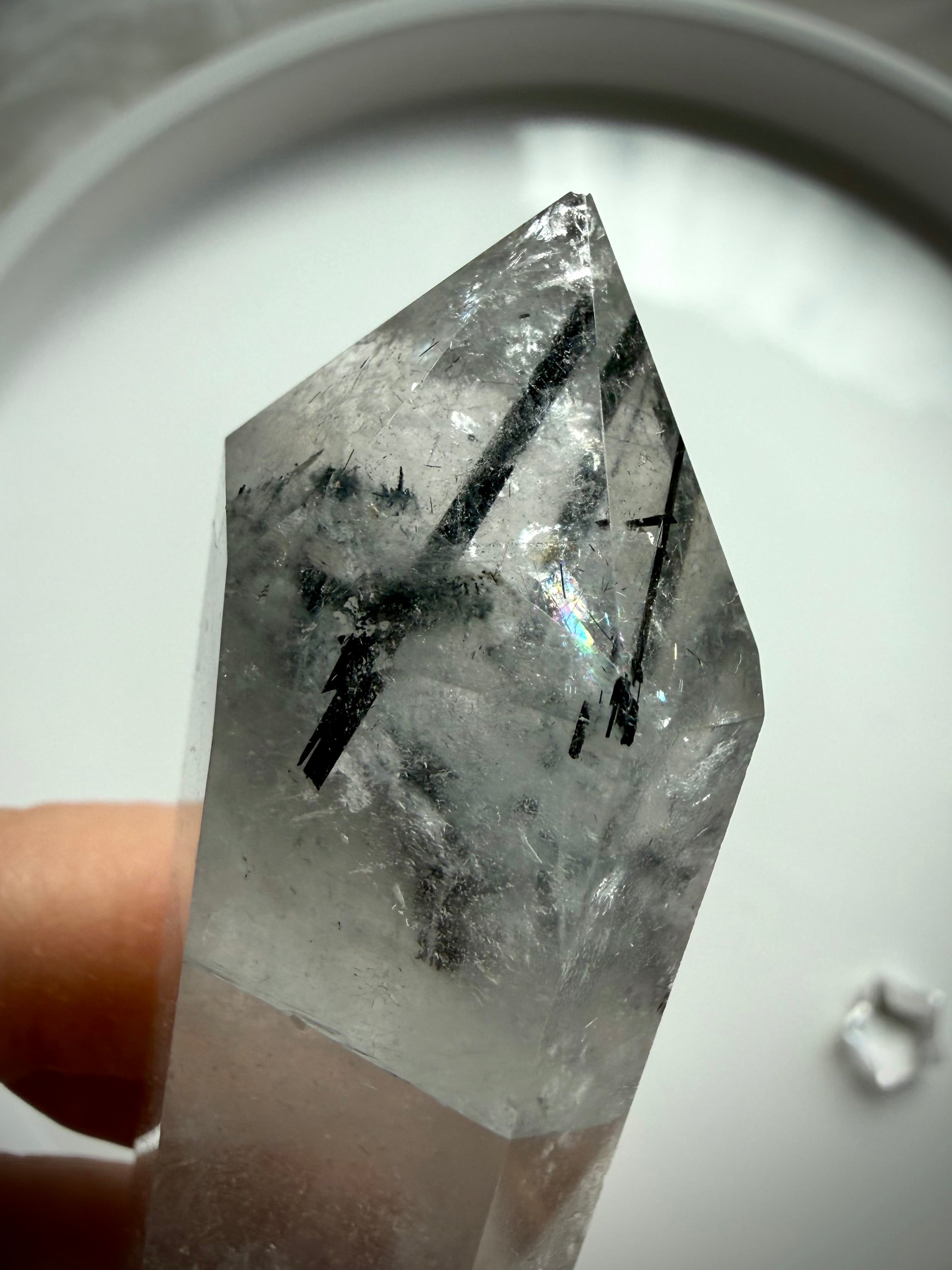 tourmalinated quartz crystal point with visible rainbow and dramatic black rutile inclusions