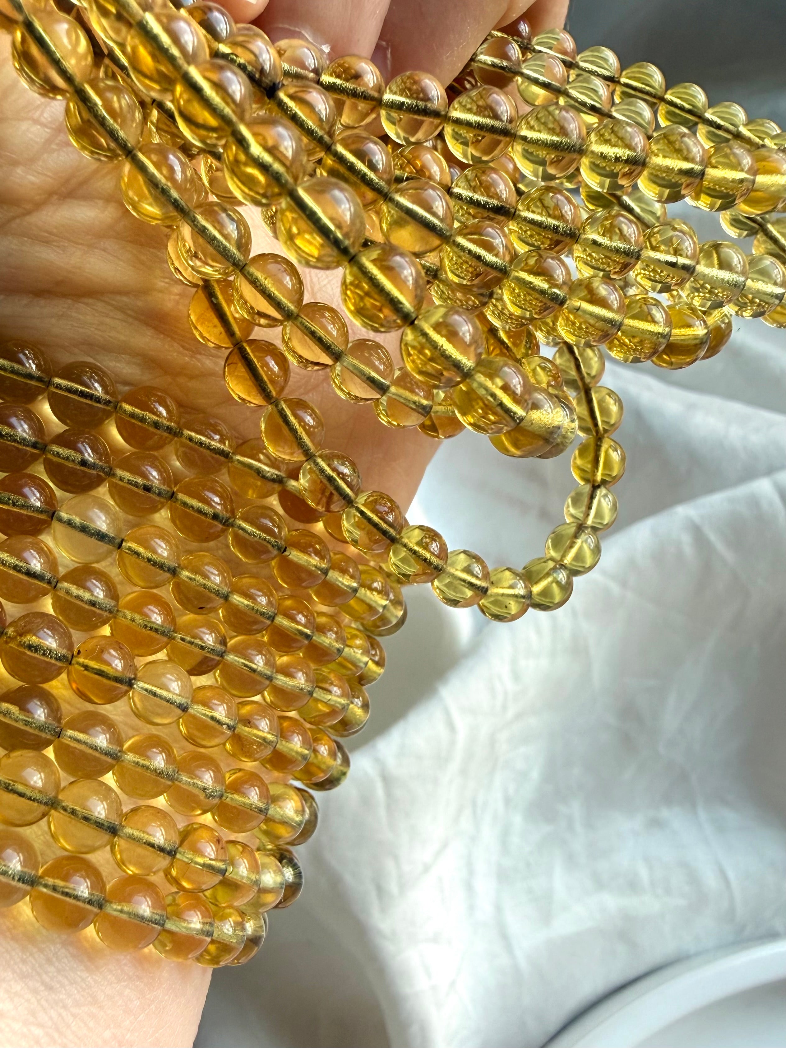 Blue Amber bracelet stack – Indonesian UV reactive amber bead bracelets glowing golden in natural light 