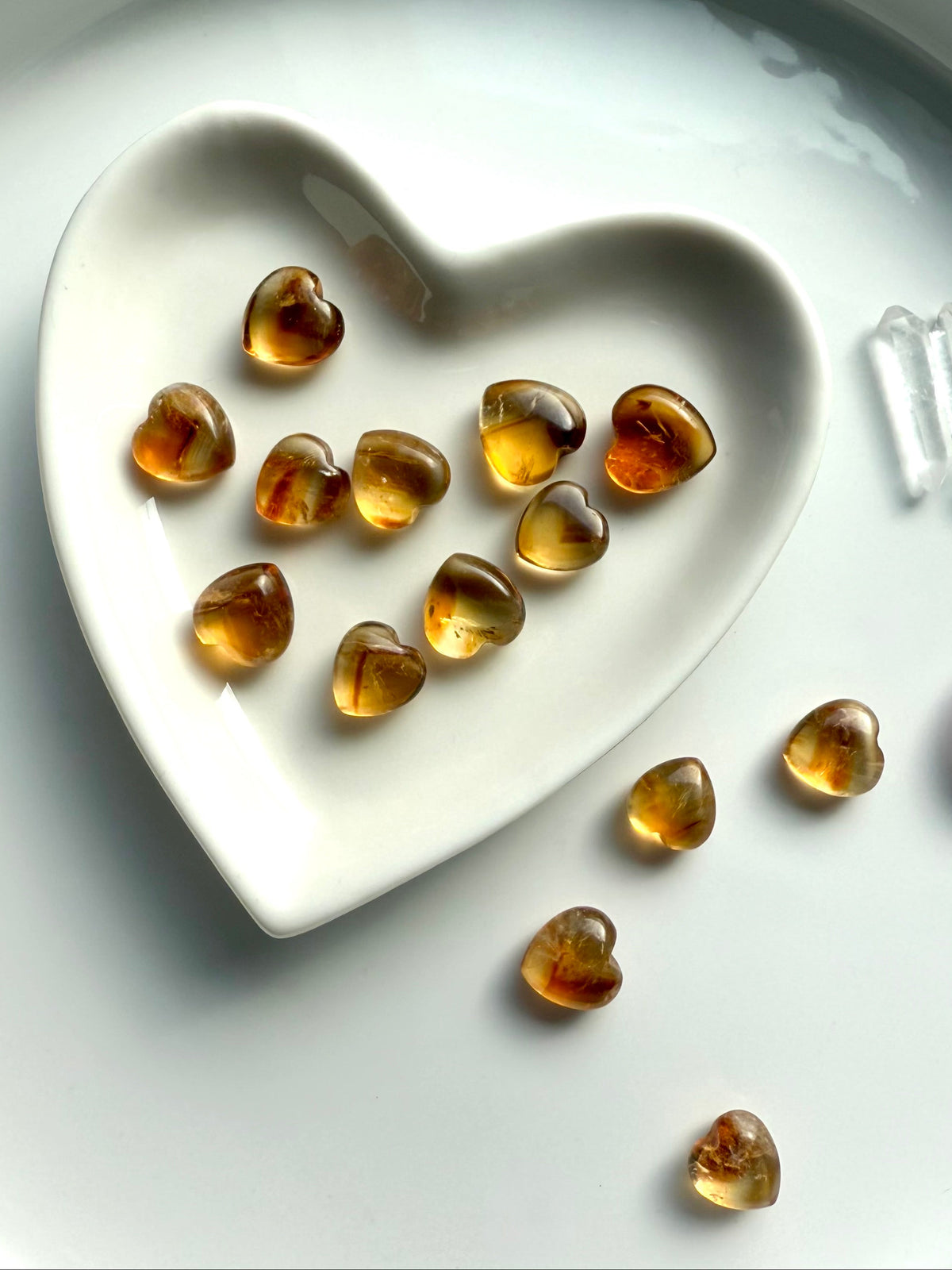 mini Citrine crystal hearts displayed in a white heart-shaped dish with clear Quartz points and glowing golden hues