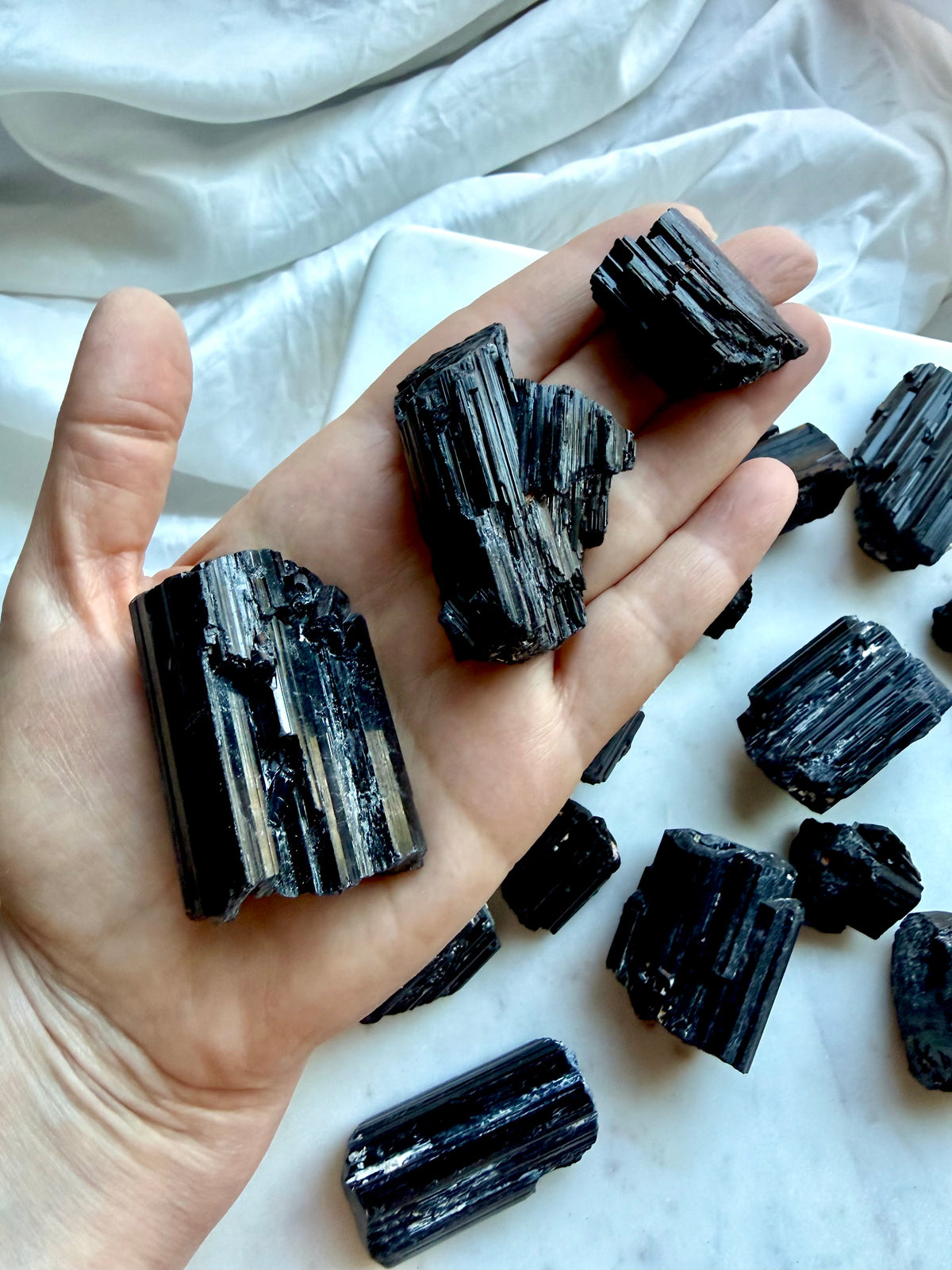 Black Tourmaline crystals held in hand for grounding, energetic protection, meditation, and energy work
