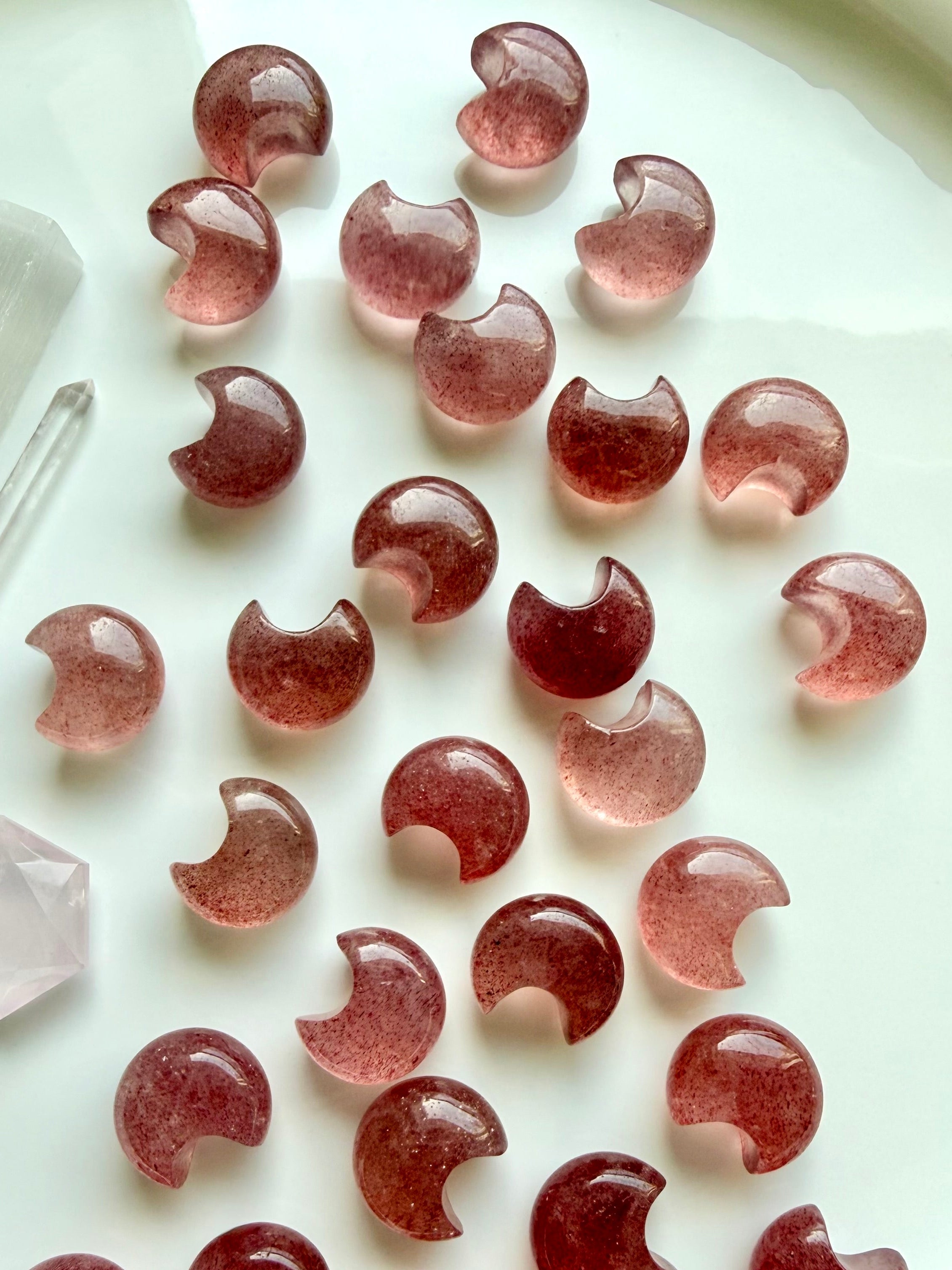 Mini Strawberry Quartz crescent moon carvings with translucent rosy pink and deep red coloring, natural inclusions and smooth polish