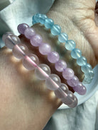 Stacked crystal bead bracelets on wrist featuring Aquamarine, lilac Kunzite and Mozambique Rose Quartz gemstone jewelry