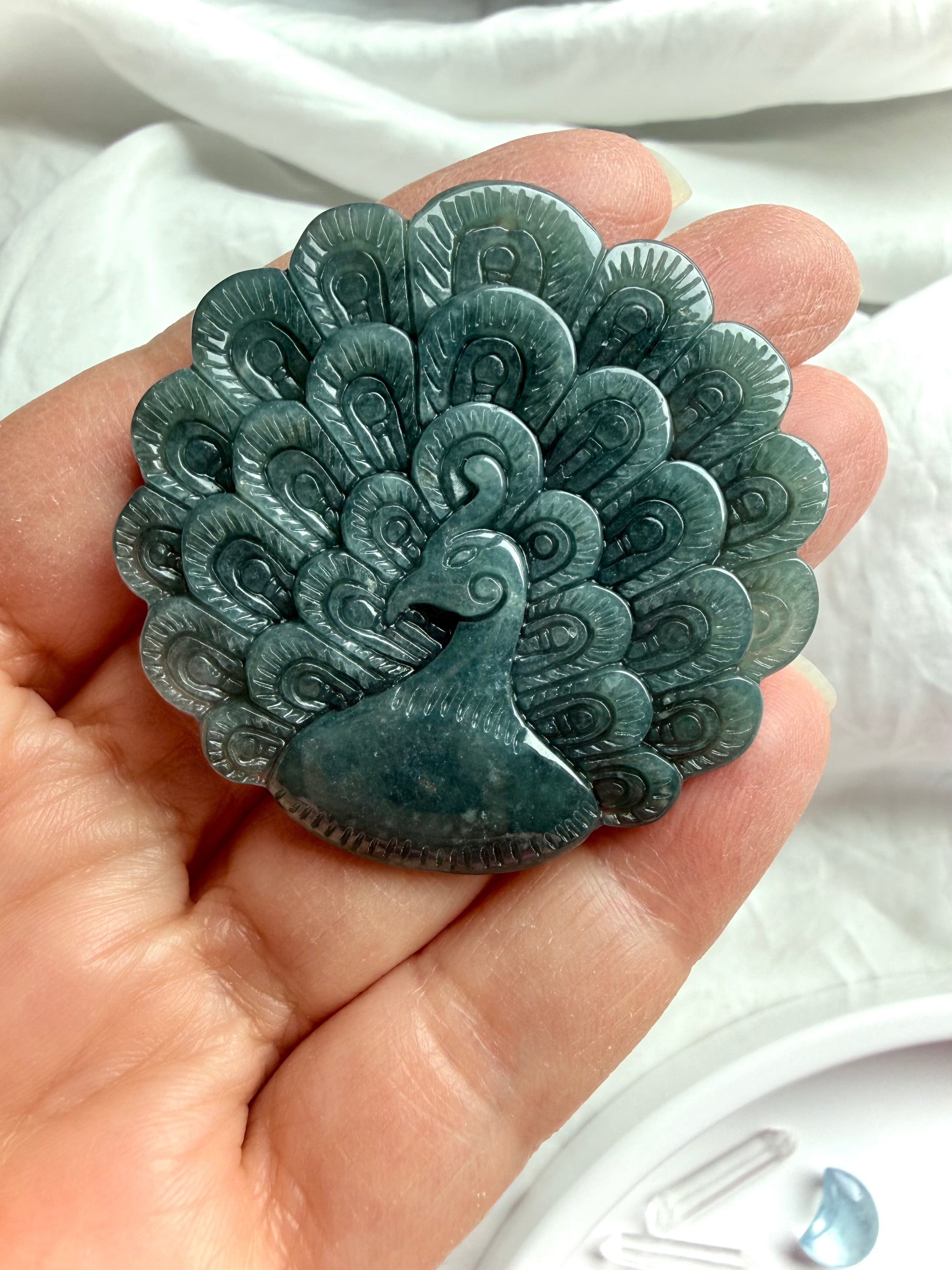 Hand-carved Blue Water Jade peacock medallion showing intricate feather details and soft blue-green tones