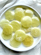 Lemon Calcite meditation stones in a white dish – polished yellow crystal discs for clarity, confidence, and solar plexus chakra healing