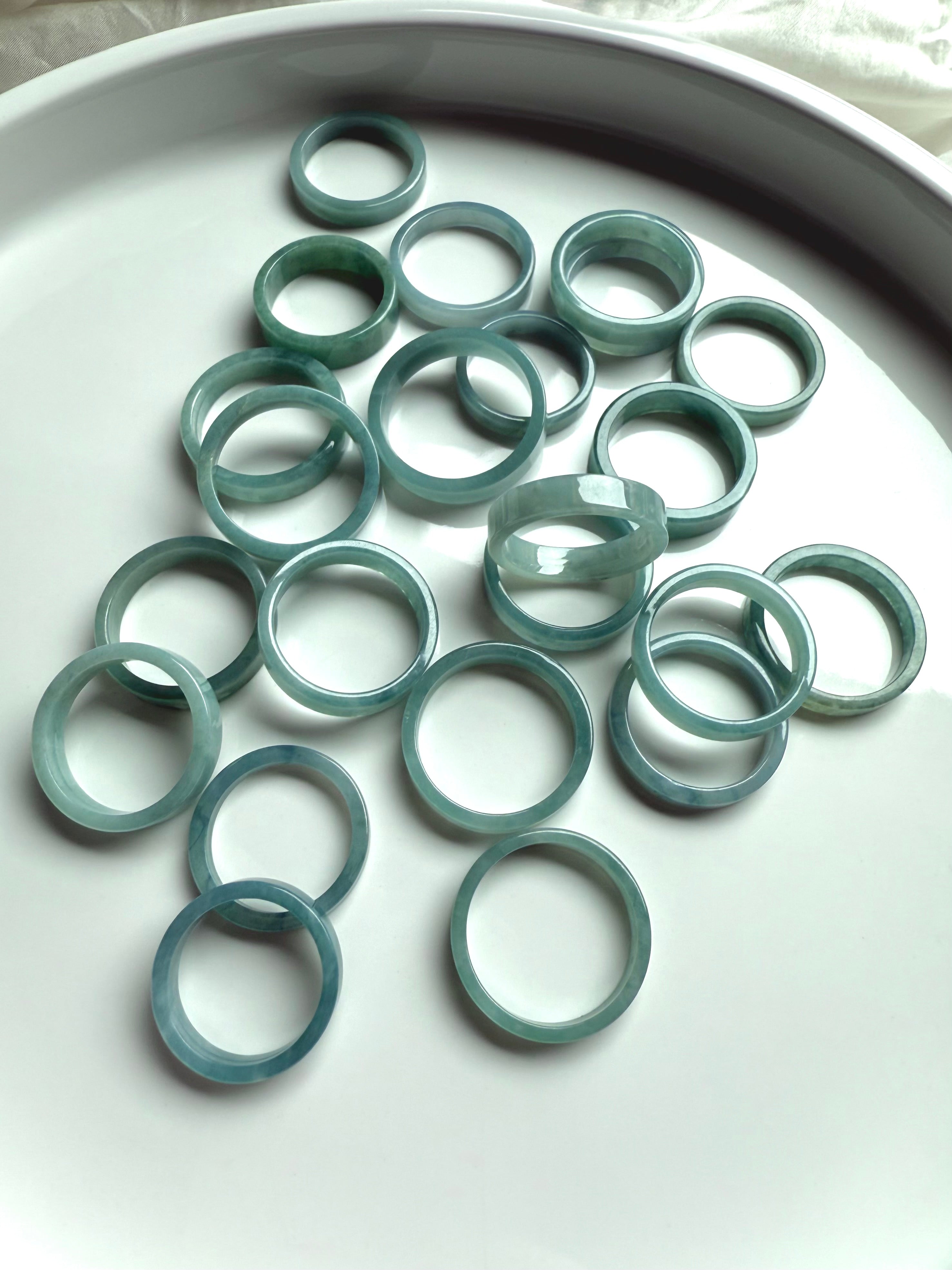 Natural jadeite rings in calming blue-green hues laid out on a white ceramic tray