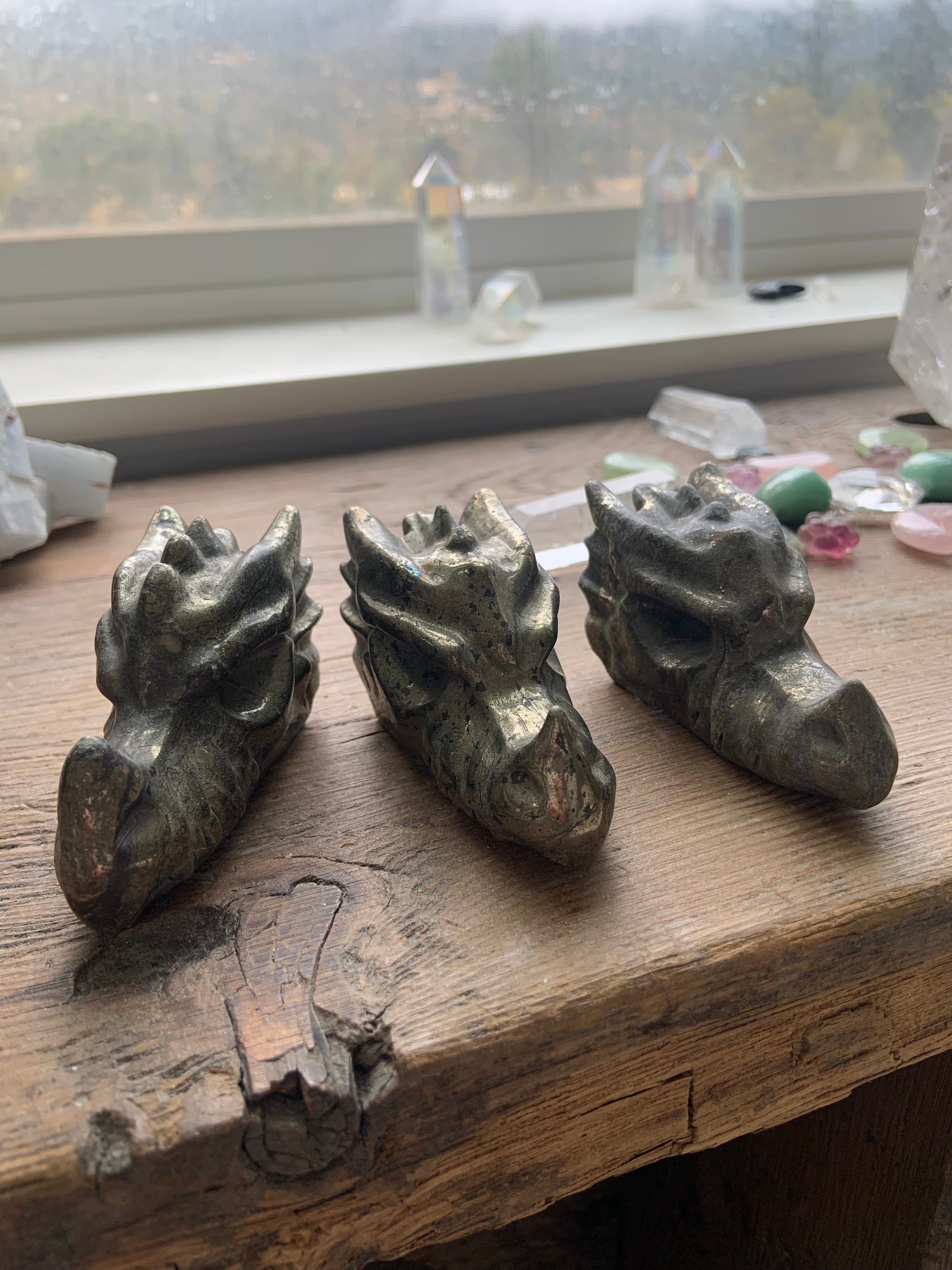 Pyrite dragon crystal carvings lined up on wooden altar, intuitively chosen protection stones