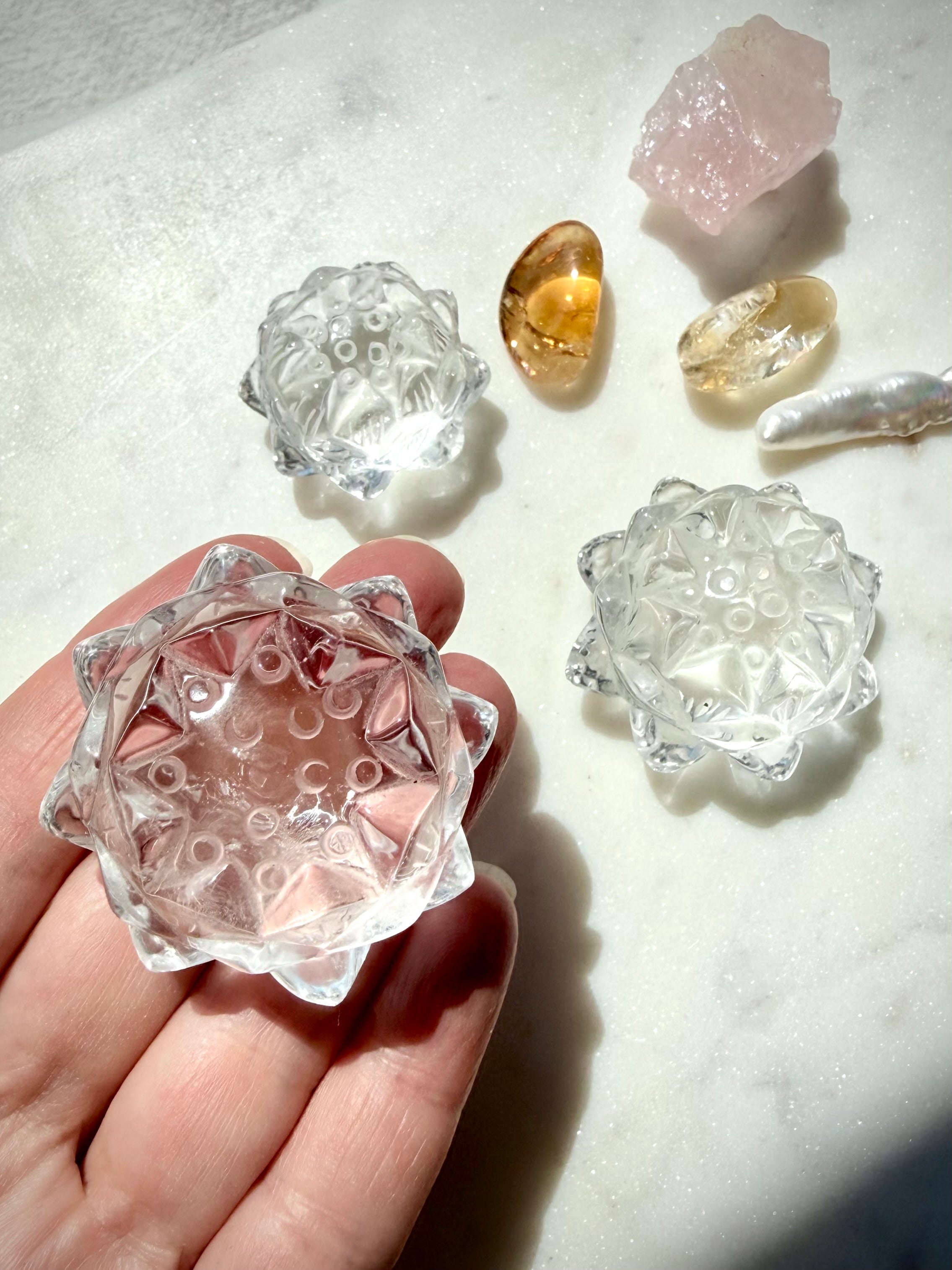 Clear Quartz lotus flower carving held with Citrine and other crystal lotuses showing natural variation and clarity