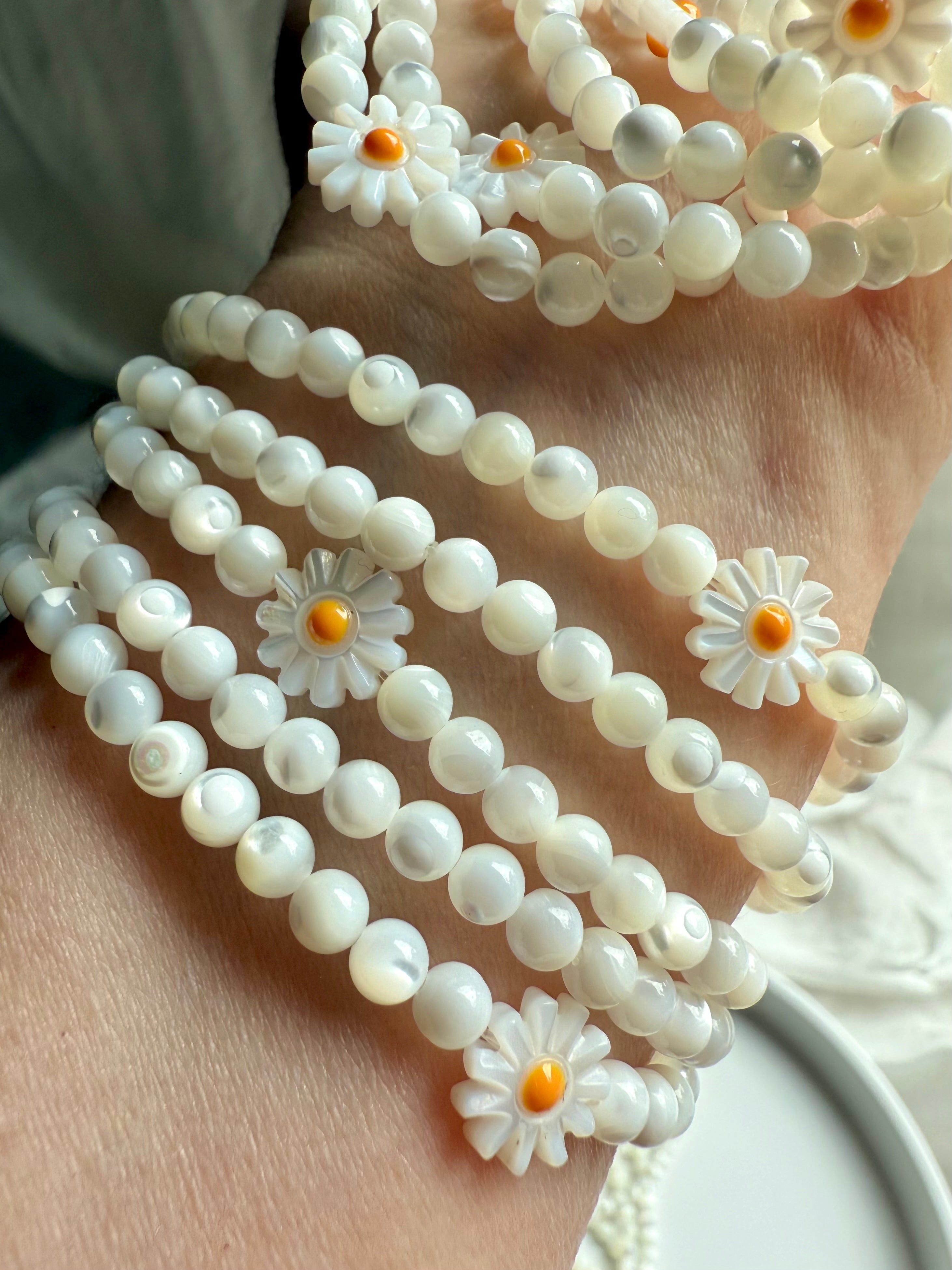 Mother of Pearl daisy bracelets stacked on wrist – opalescent shell bead jewelry for lighthearted boho style