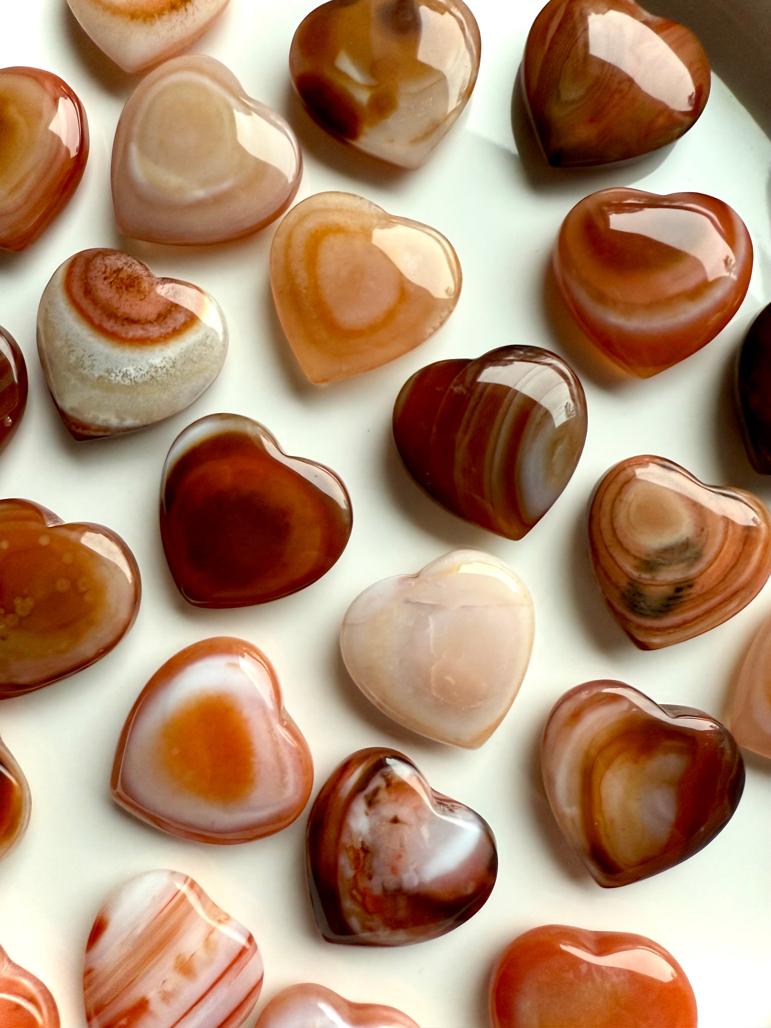 Polished mini Carnelian hearts highlighting natural agate banding, warm orange sacral chakra crystal for emotional balance and joy