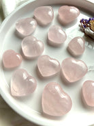 Rose quartz crystal hearts styled on a white plate with floral accents, heart chakra stones for self love