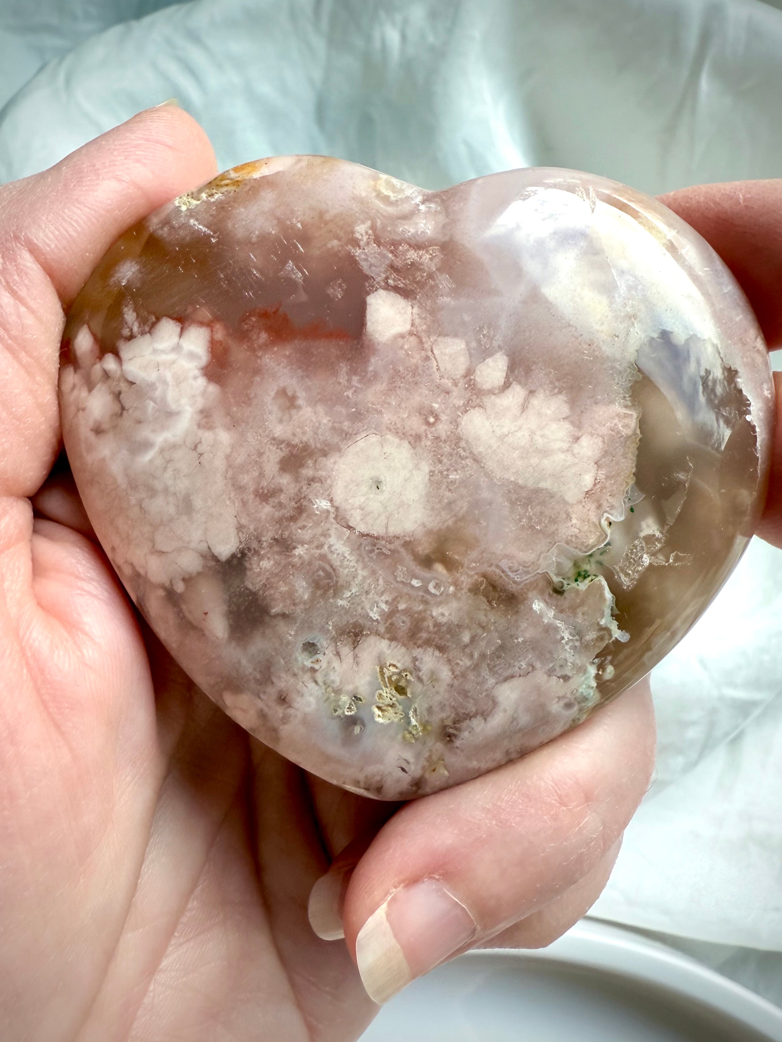 One-of-a-kind Pink Amethyst and Flower Agate heart crystal shown front-facing in hand for size reference