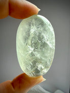 Prasiolite palm stone backlit to reveal luminous green clarity and internal crystal textures