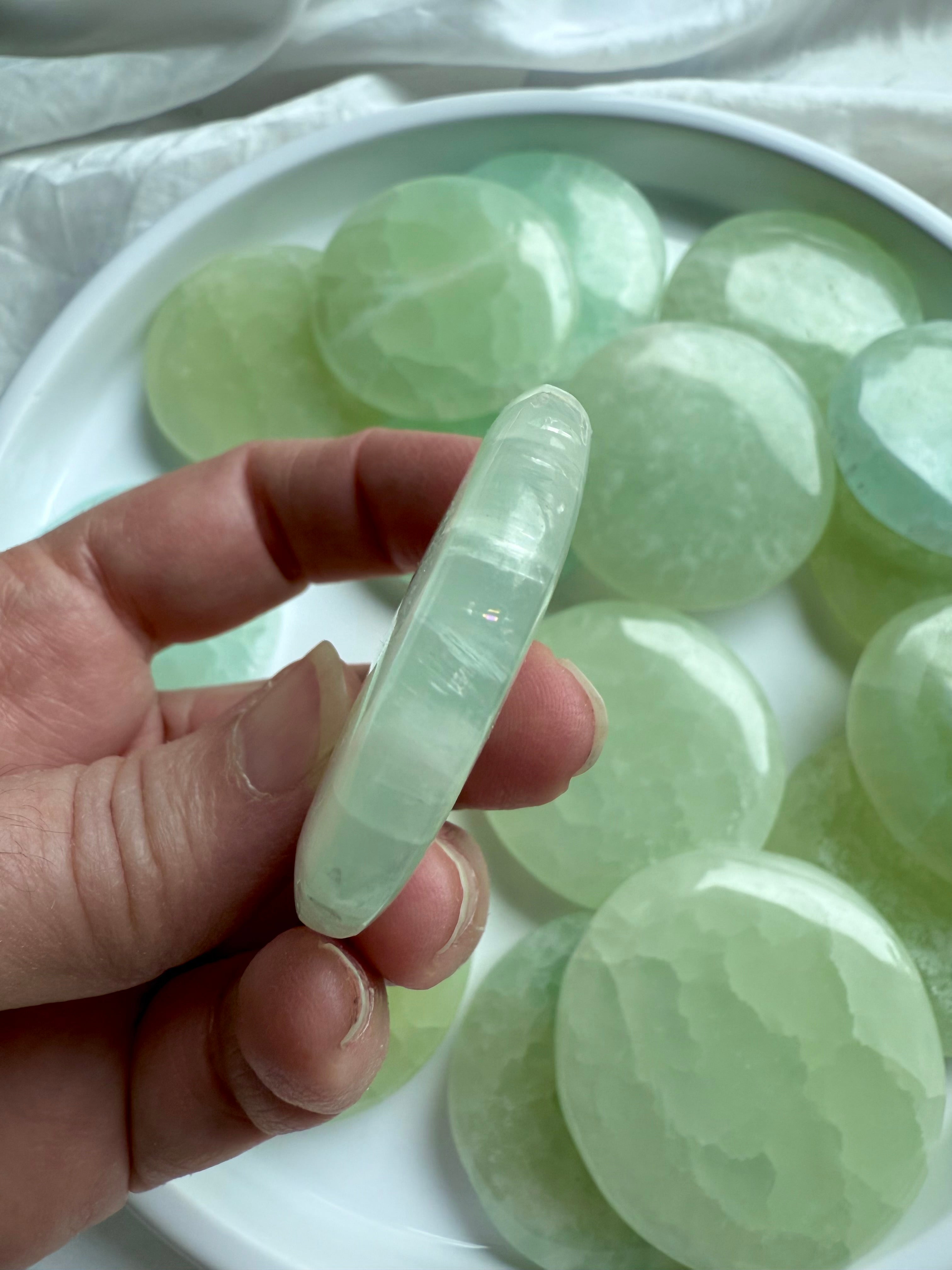 Side profile of a thin Pistachio Calcite meditation stone, showing layered bands and translucent clarity