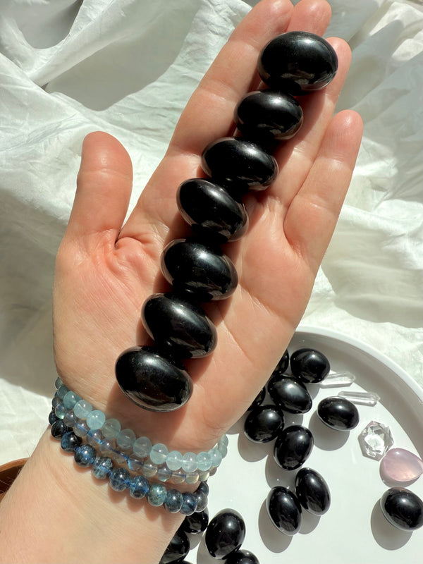 Black Obsidian Tumbles shown on my hand for scale, photographed in natural light