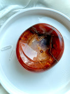 Carnelian crystal offering bowl on a white dish with clear quartz points – sacral chakra crystal for energy flow