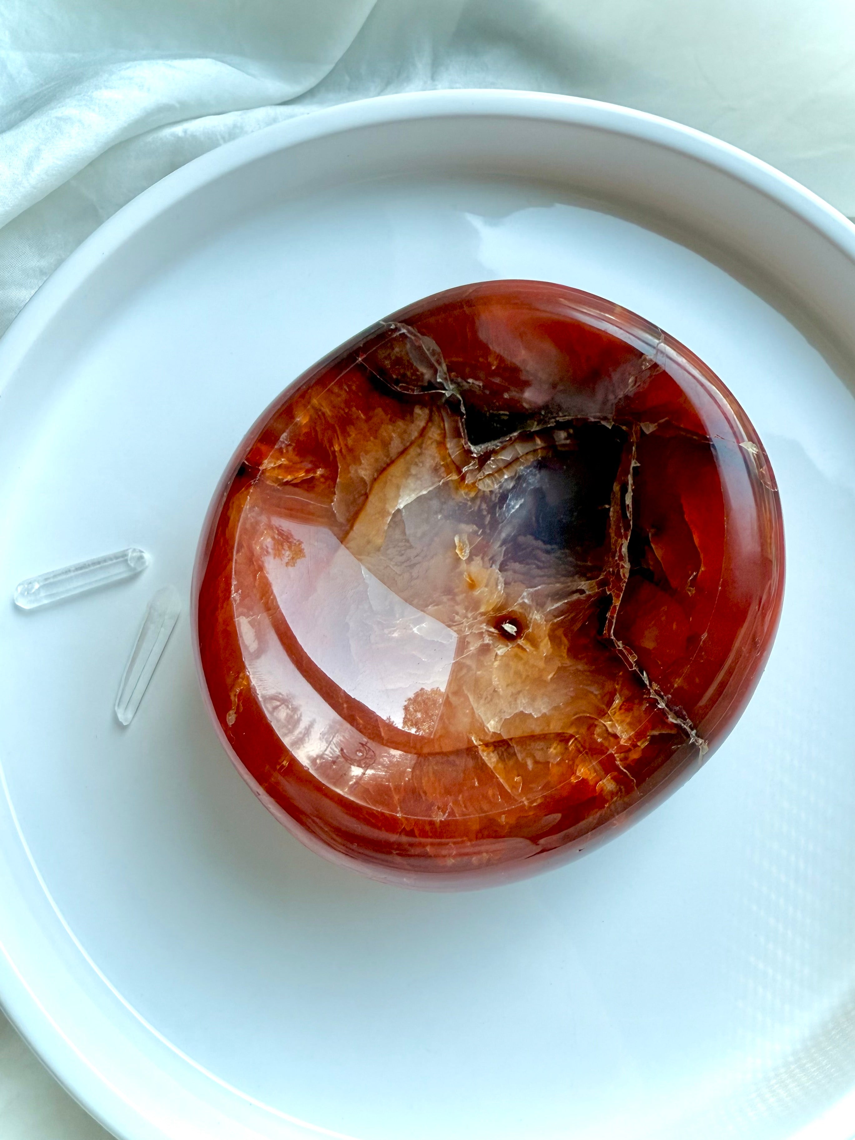 Carnelian crystal offering bowl on a white dish with clear quartz points – sacral chakra crystal for energy flow