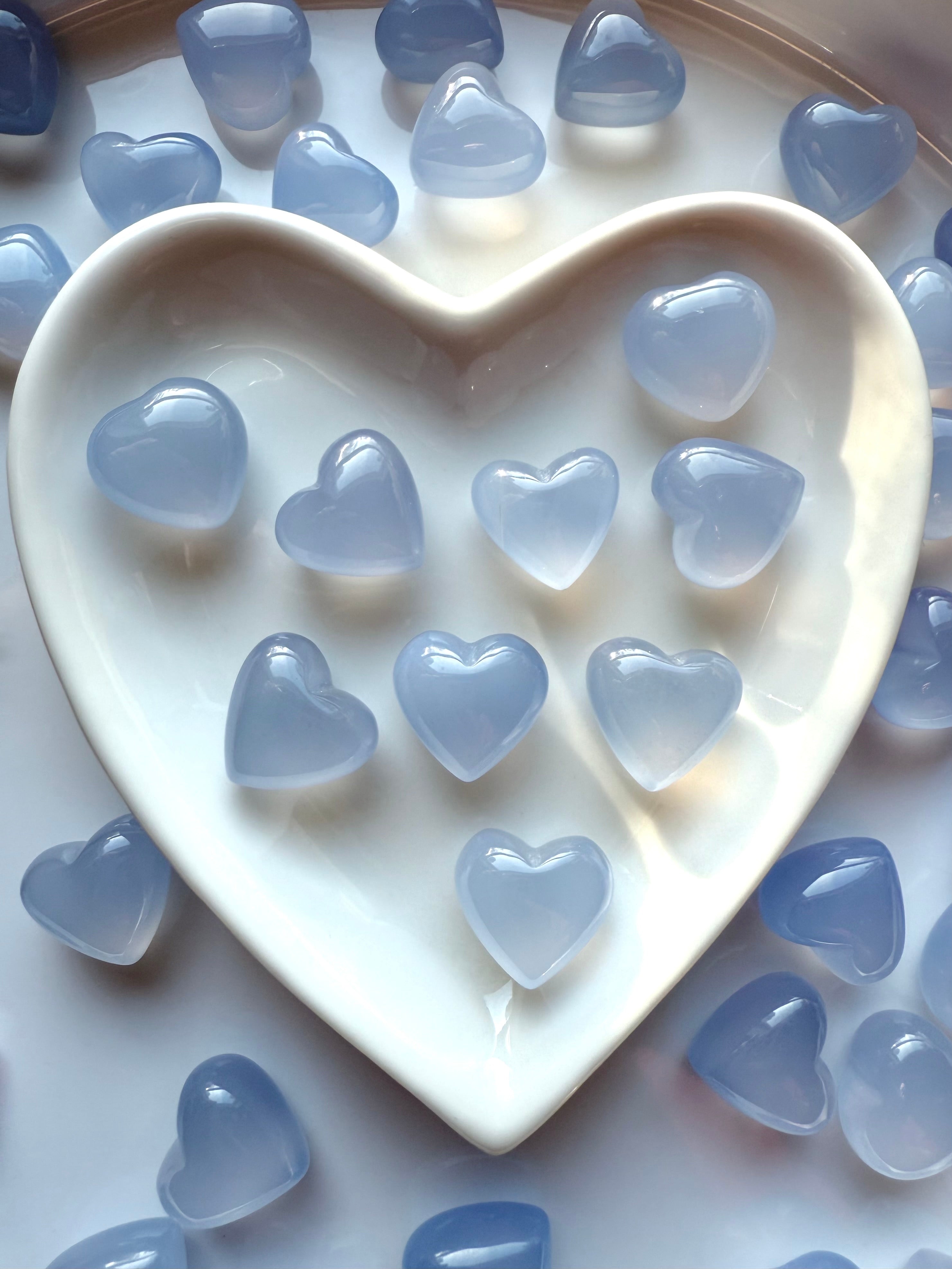 Mini Blue Chalcedony heart crystals displayed in a white heart-shaped ceramic dish, Throat Chakra crystals for gentle self-expression