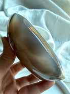 Orca Agate offering bowl held in hand at an angled view, highlighting natural druzy pockets and flowing ocean-like banding