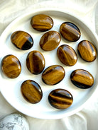 Assortment of Tiger’s Eye palm stones with rich golden chatoyancy for grounding, confidence, and abundance