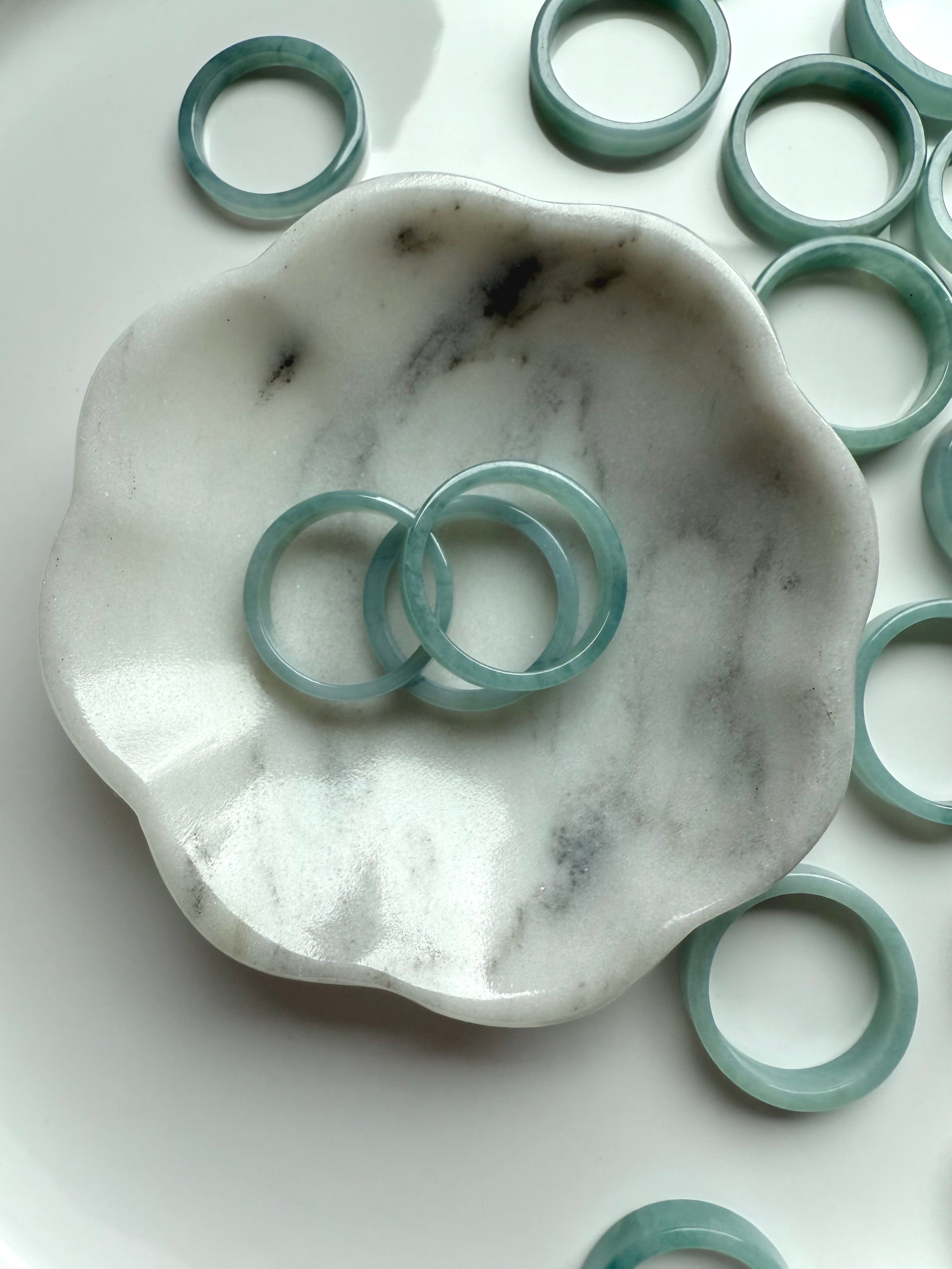 Blue Water Jade rings on a marble flower dish with soft green-blue hues and natural texture