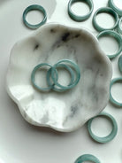 Blue Water Jade rings on a marble flower dish with soft green-blue hues and natural texture