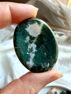 Moss Agate oval worry stone held in hand with translucent quartz, forest green inclusions and landscape patterns