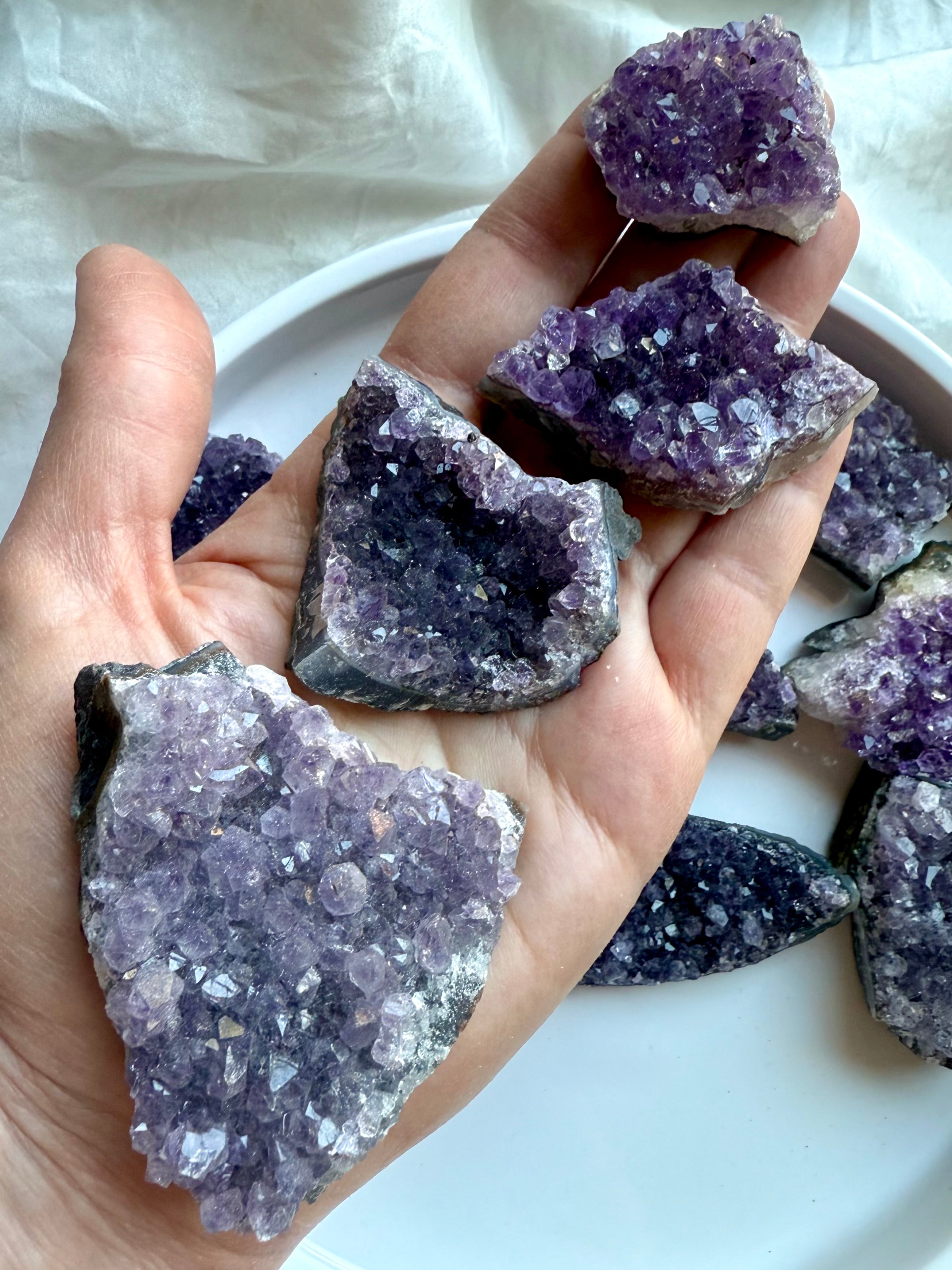 Sparkly Amethyst geode clusters in assorted sizes shown in hand for scale