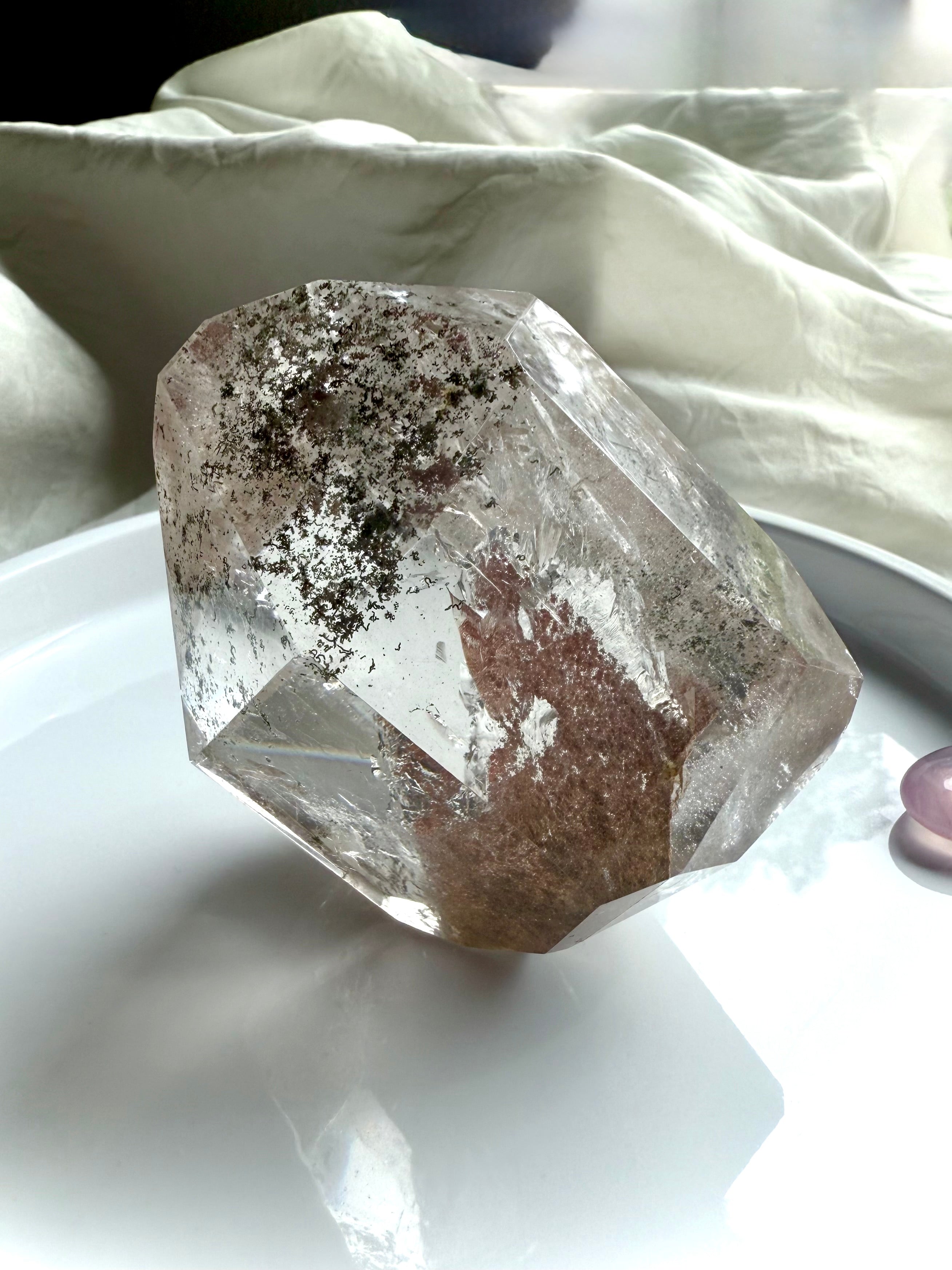 A Lodolite Garden Quartz Crystal shown standing on one of the side angles to highlight the phantom 