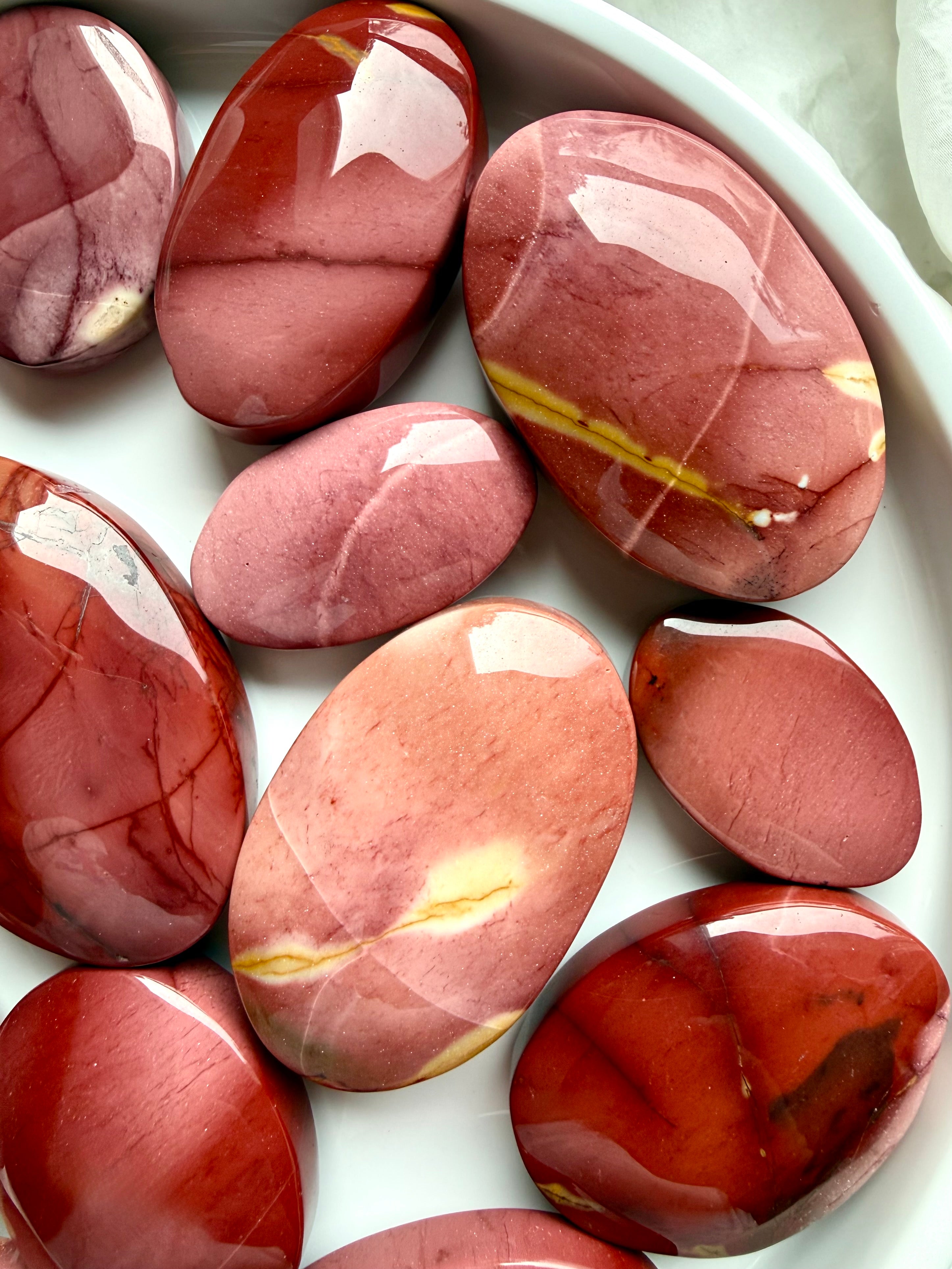 assorted Mookaite Jasper palm stones with warm earthy patterns and polished finish for stability and personal strength