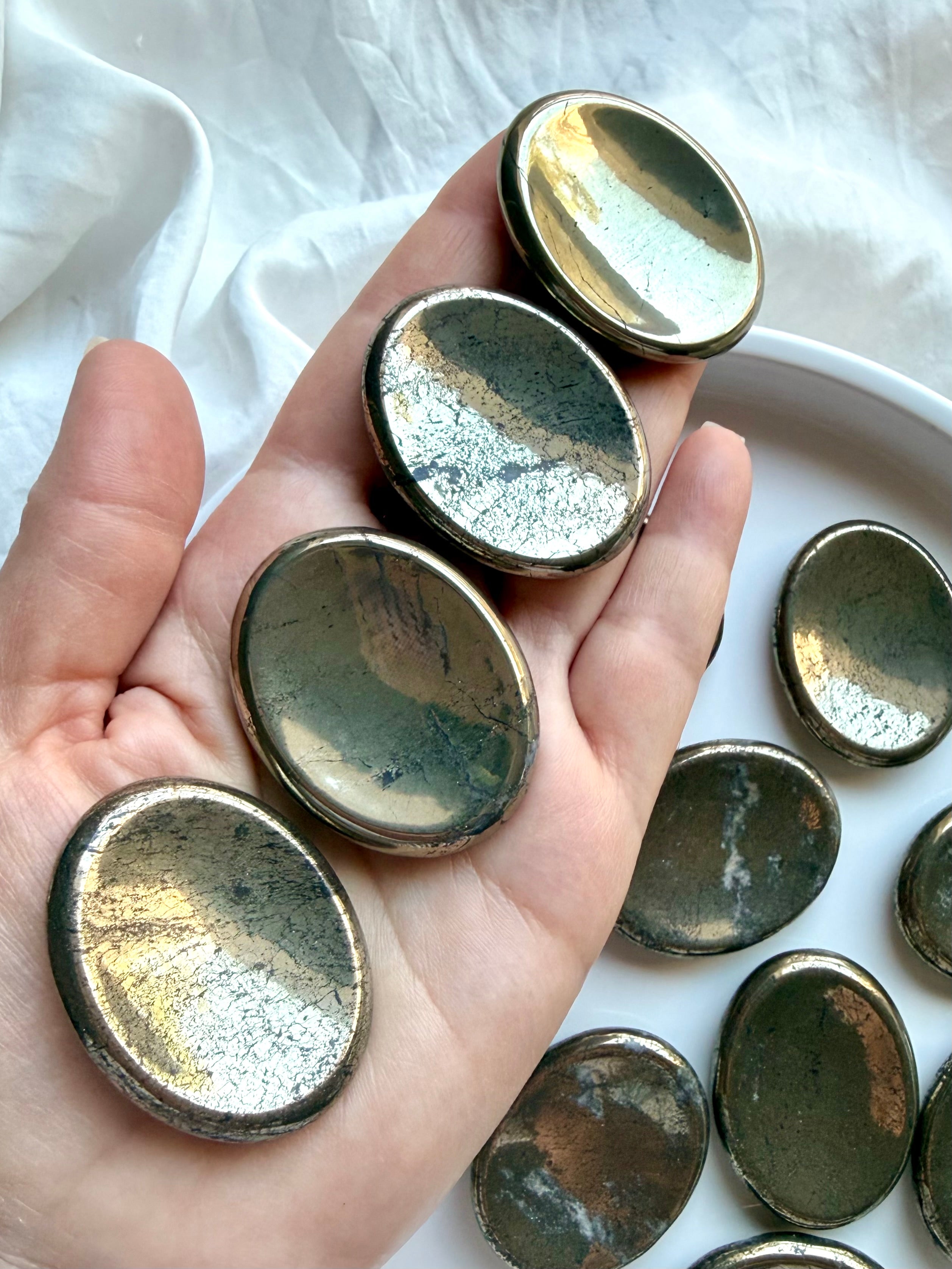 Polished Pyrite worry stones shown on hand highlighting metallic gold sheen and natural variation