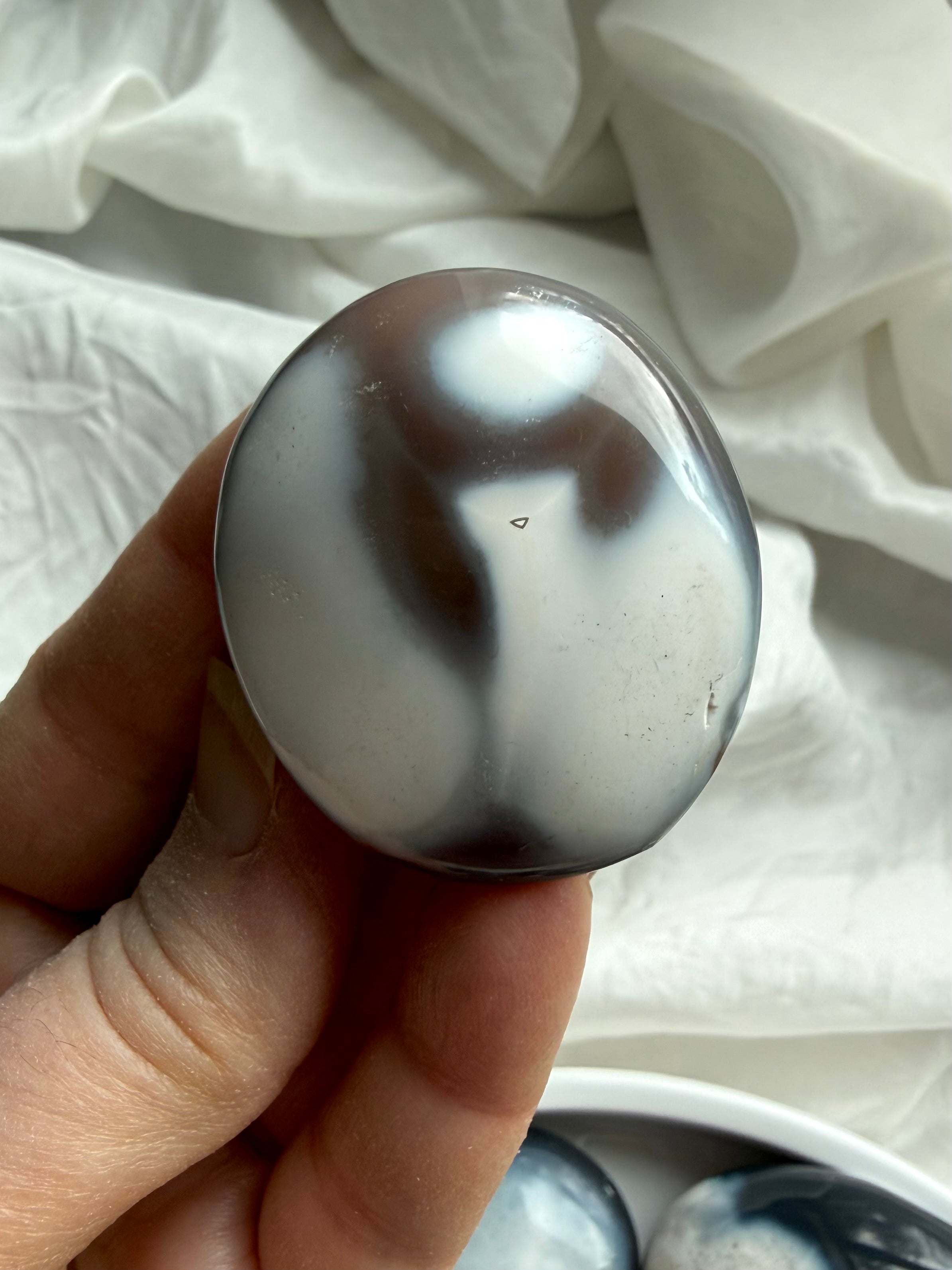 Orca Agate palm stone with black and white patterns, a calming crystal for forgiveness, emotional grounding, and inner peace