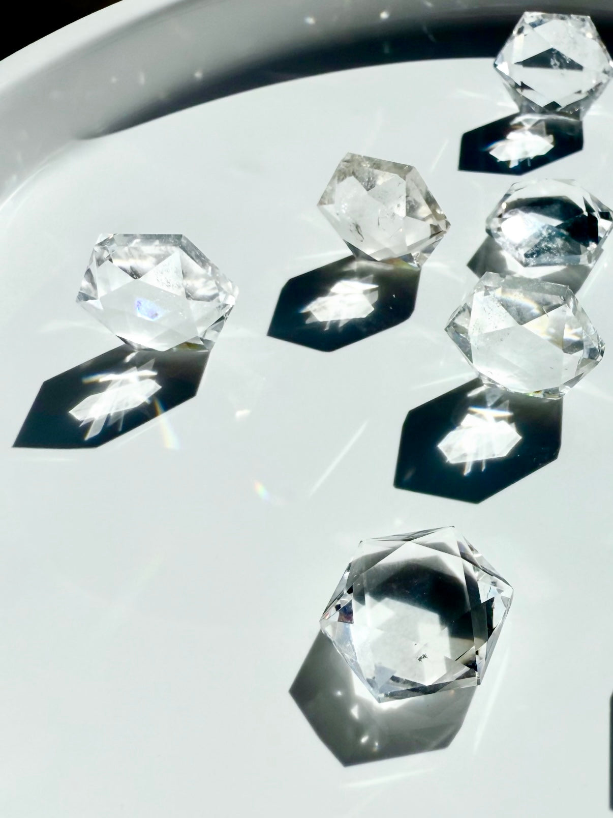 Angled view of multiple Clear Quartz hexagons standing on edges, casting radiant hexagonal light and shadows