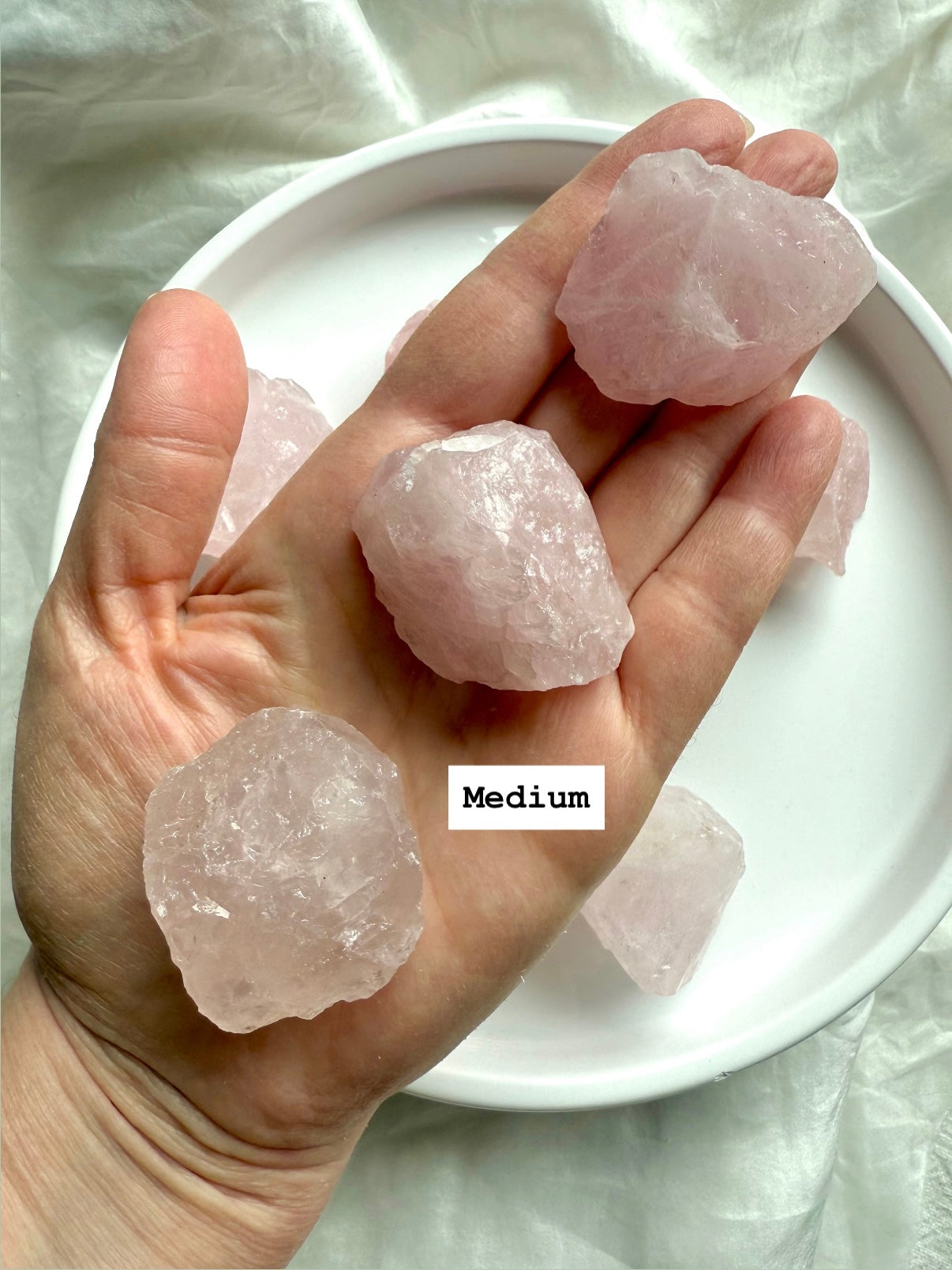 Hand holding three medium raw Rose Quartz chunks, natural Madagascar crystals for Heart Chakra healing and emotional balance
