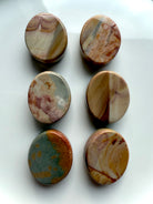 Assorted Polychrome Jasper cabochons shown from the back to highlight organic markings and desert-tone patterns — earthy crystals for balance and stability.