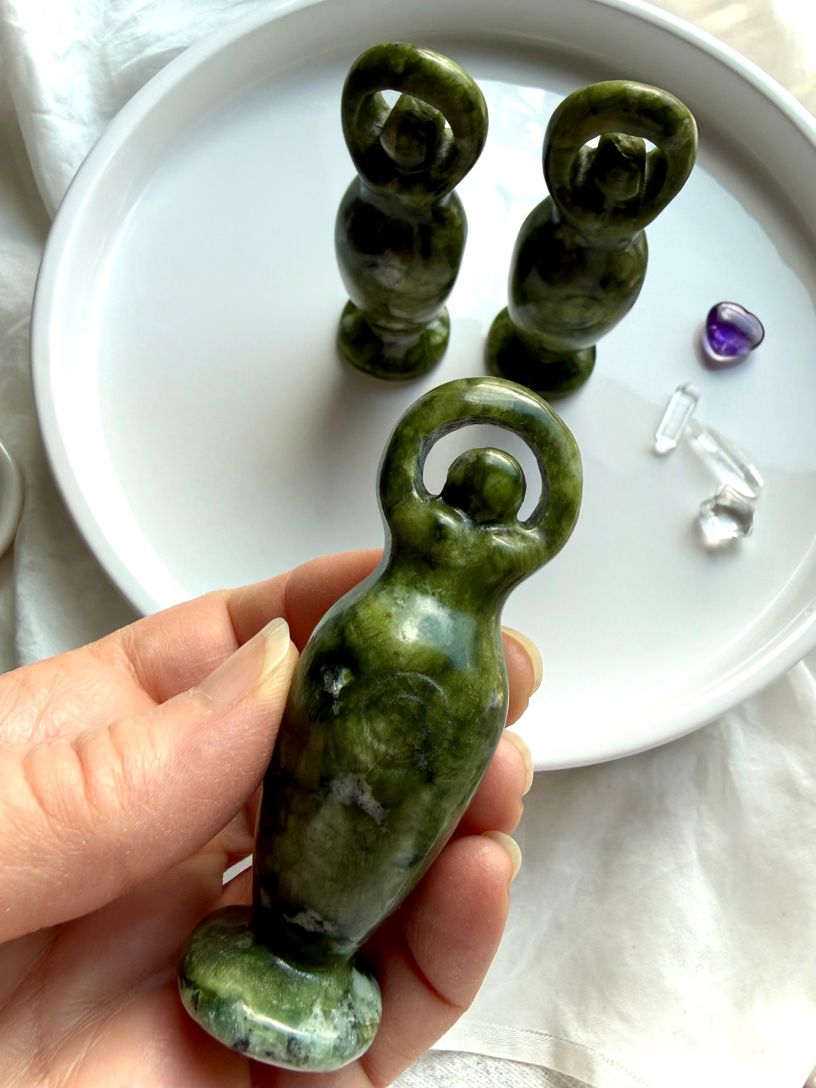 close up nephrite jade goddess carving showing natural green jade patterns and polished crystal detail