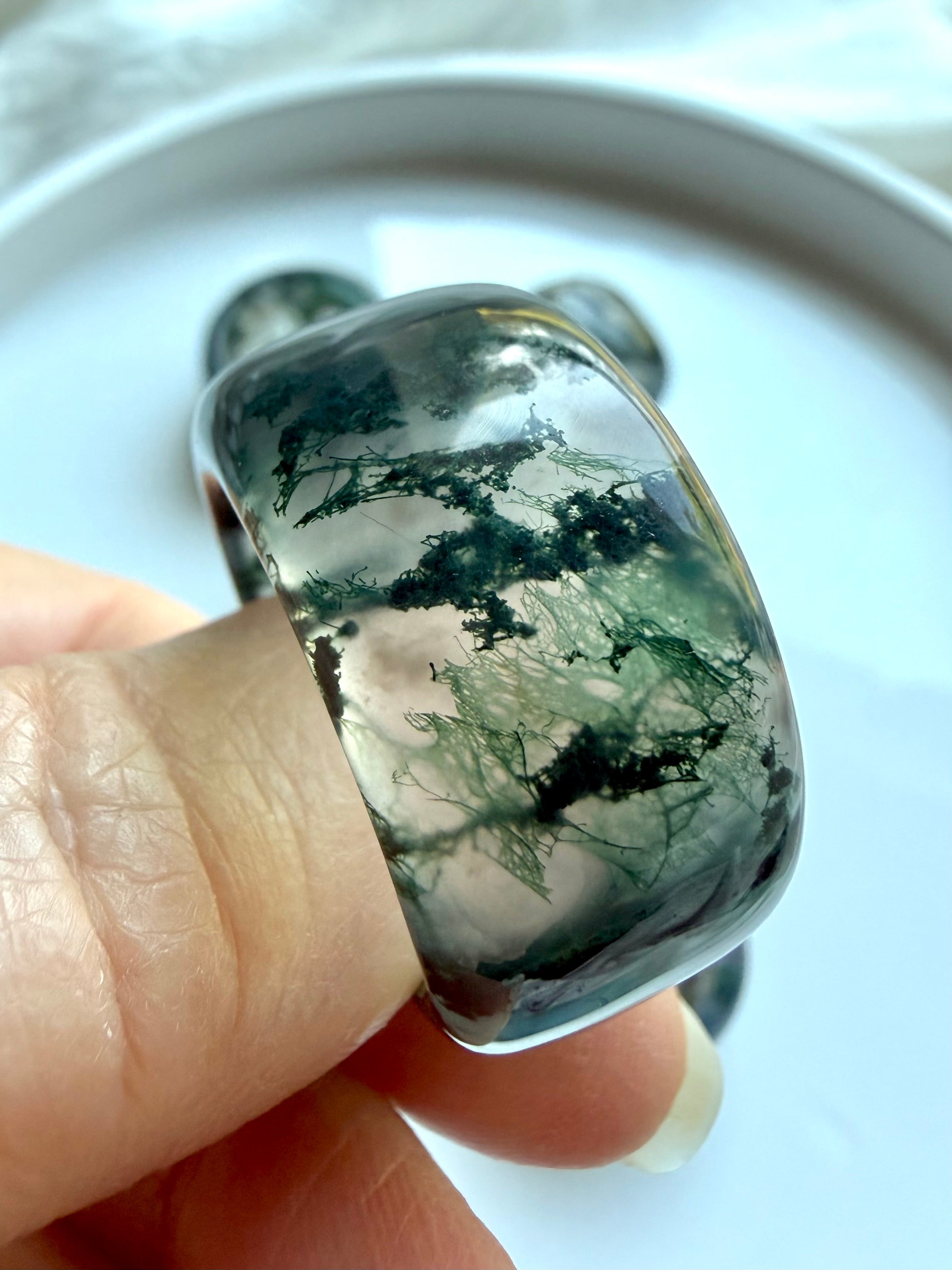 close-up moss agate statement ring worn on finger with scenic dendritic inclusions and polished translucent finish