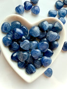 White heart bowl overflowing with mini Blue Kyanite crystal hearts, silvery blue shimmer stones for meditation and chakra healing