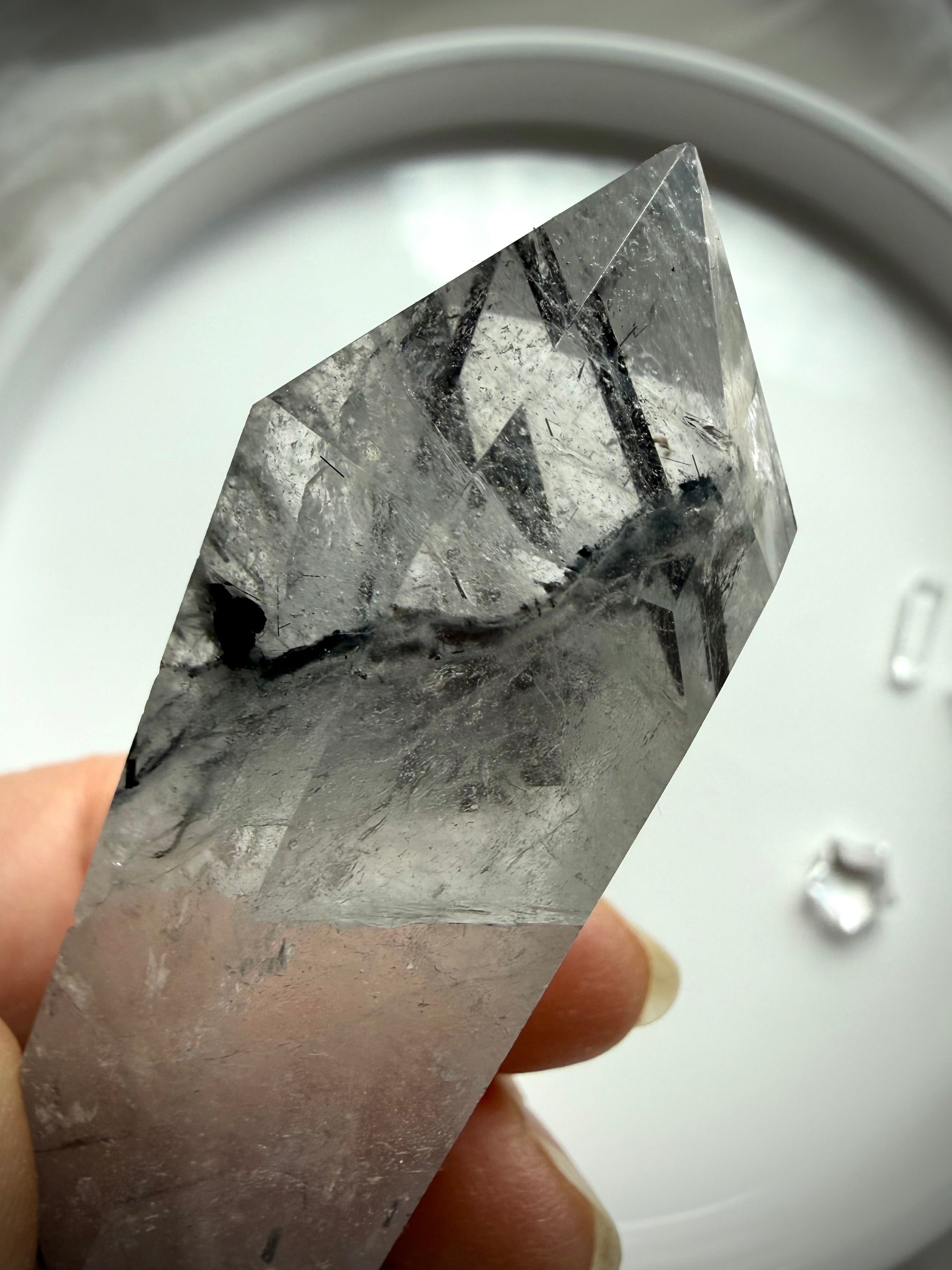 black tourmaline in quartz DT crystal point held in hand showing natural inclusions
