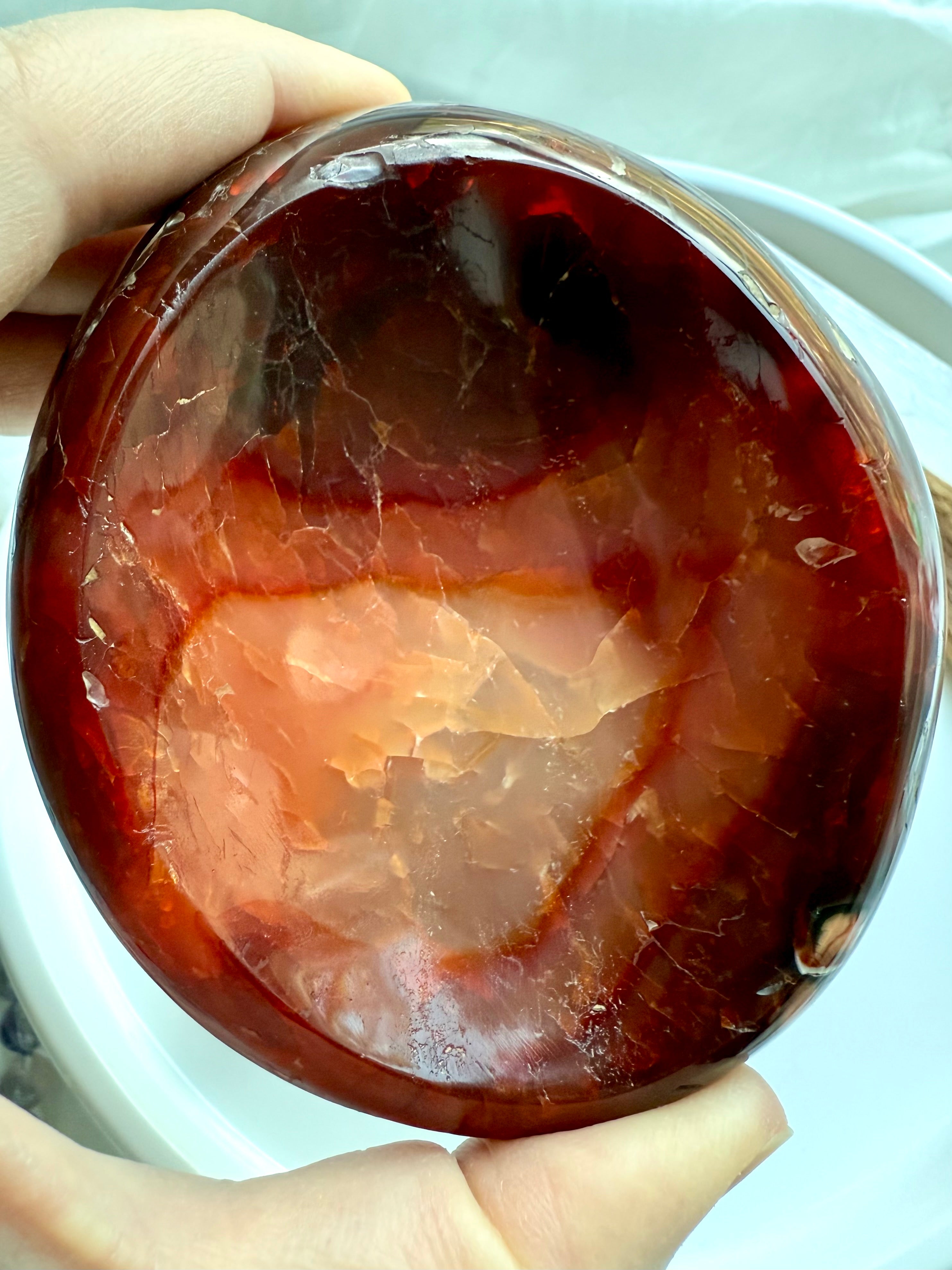 Close-up of a deep red and golden-orange Carnelian stone bowl with polished surface and natural internal textures – perfect for healing decor.