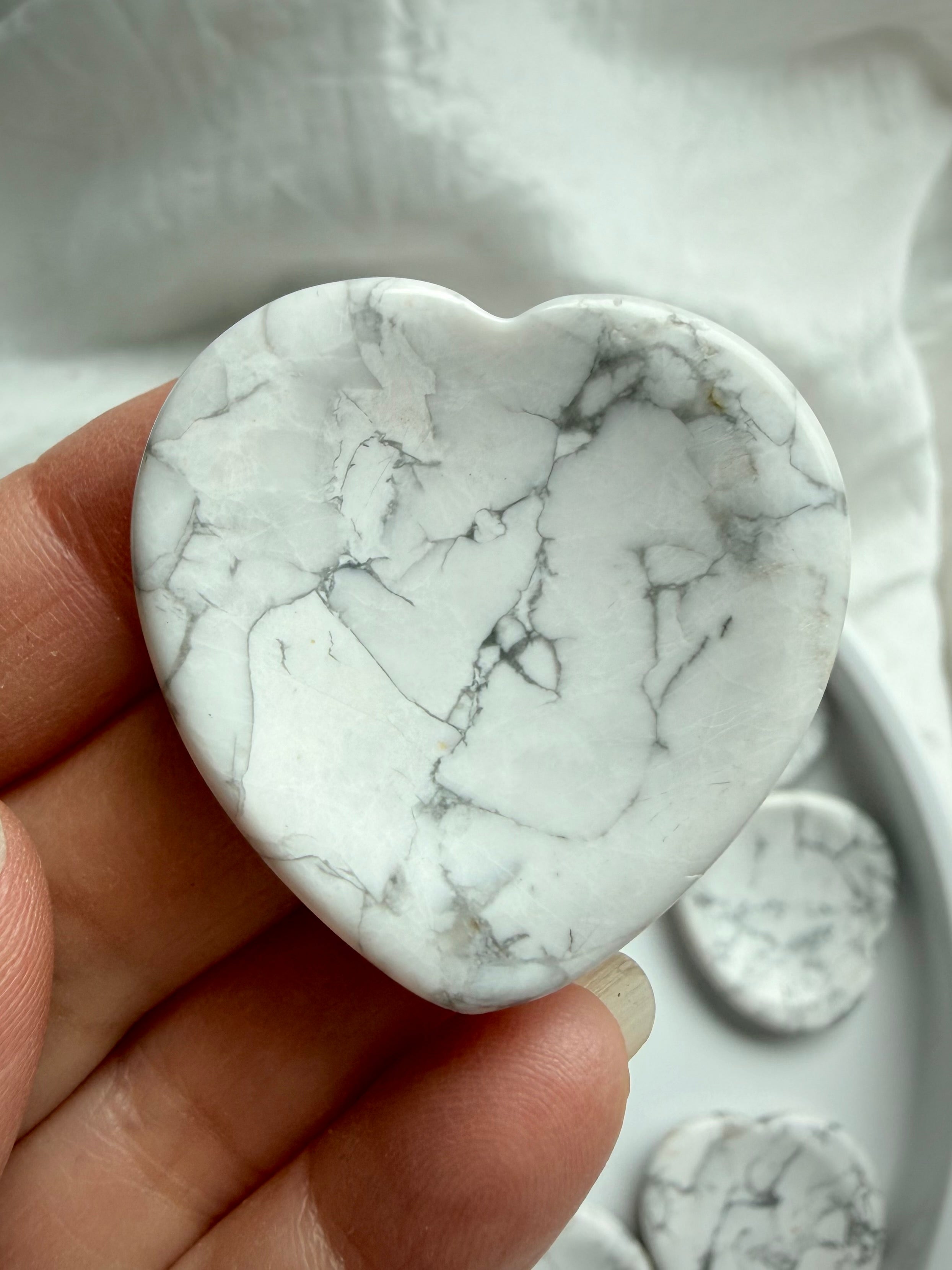 Howlite heart worry stone in hand with natural gray veining polished crystal