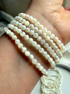 Side view of Mother of Pearl bracelets on wrist, showing glossy round shell beads with natural iridescence